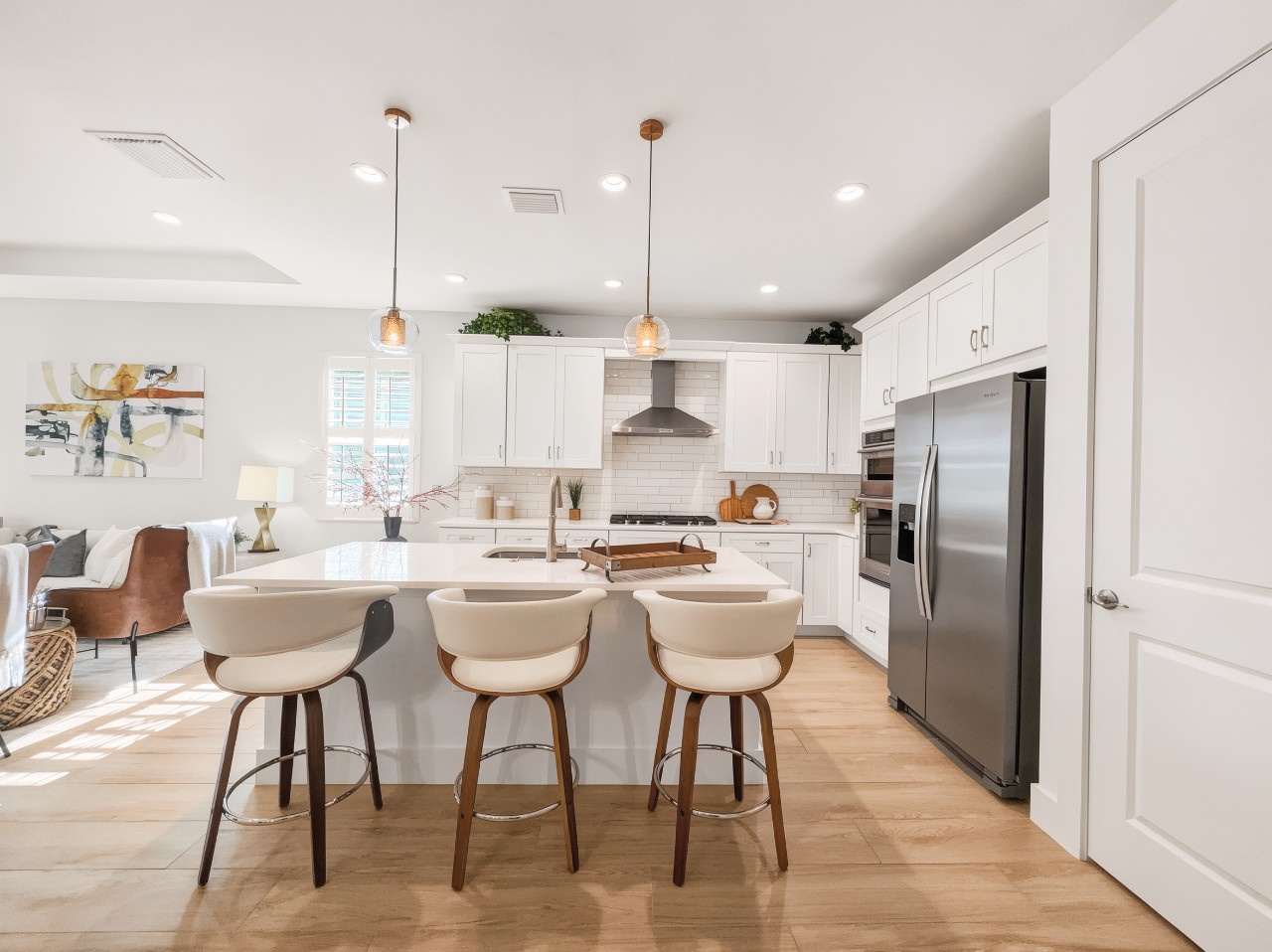 Gather around the spacious island where crisp white cabinetry and warm wood floors create your inviting culinary retreat. Pendant lights cast a welcoming glow over the gleaming countertops, ready for your morning coffee or evening meal prep.