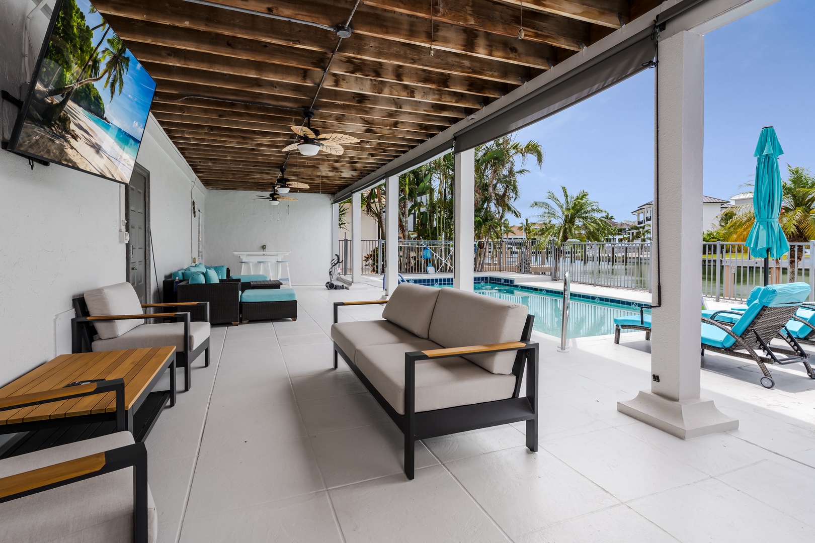 Step into your private poolside retreat where coastal breezes and tropical palms frame your relaxation. Lounge under exposed wood beams, sip your morning coffee, and enjoy seamless indoor-outdoor living just steps from the sparkling water.