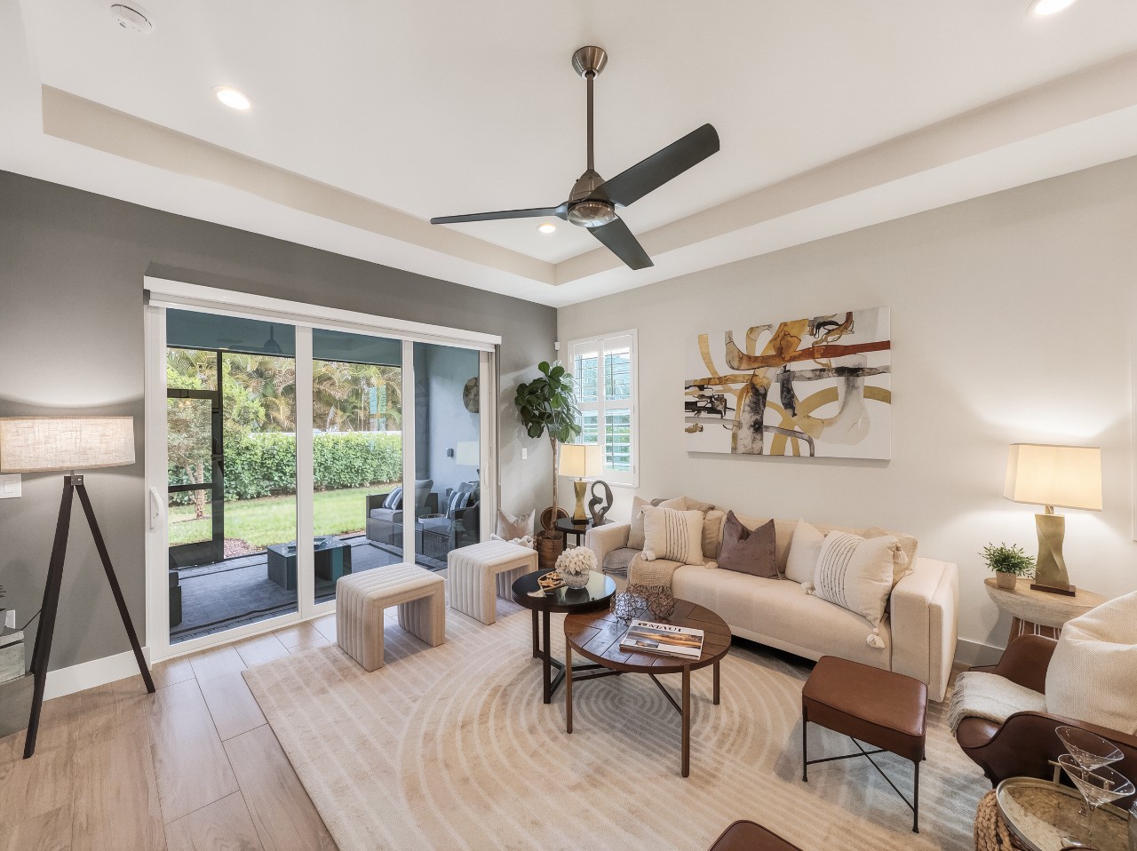 Relax in your bright, airy living room, where sleek modern design meets comfort. Sink into the plush sofa, enjoy the cool breeze from the ceiling fan, and step through glass doors to your private patio overlooking lush greenery.