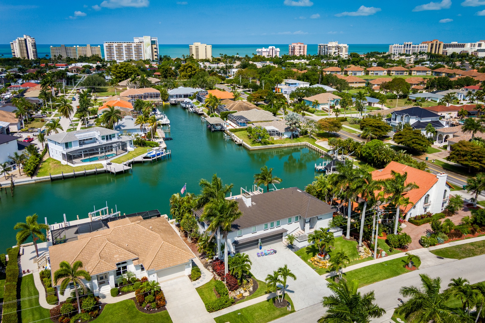 Aerial view of a waterfront vacation rental neighborhood with private docks, tropical landscaping, and ocean access in a coastal resort community.