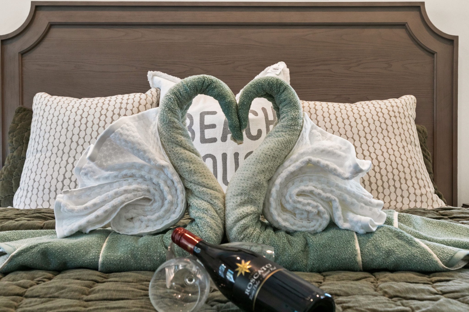 Welcome to a bedroom where thoughtful touches await you. Fresh towels arranged in a welcoming display promise comfort, while complimentary wine adds a celebratory note to your stay.