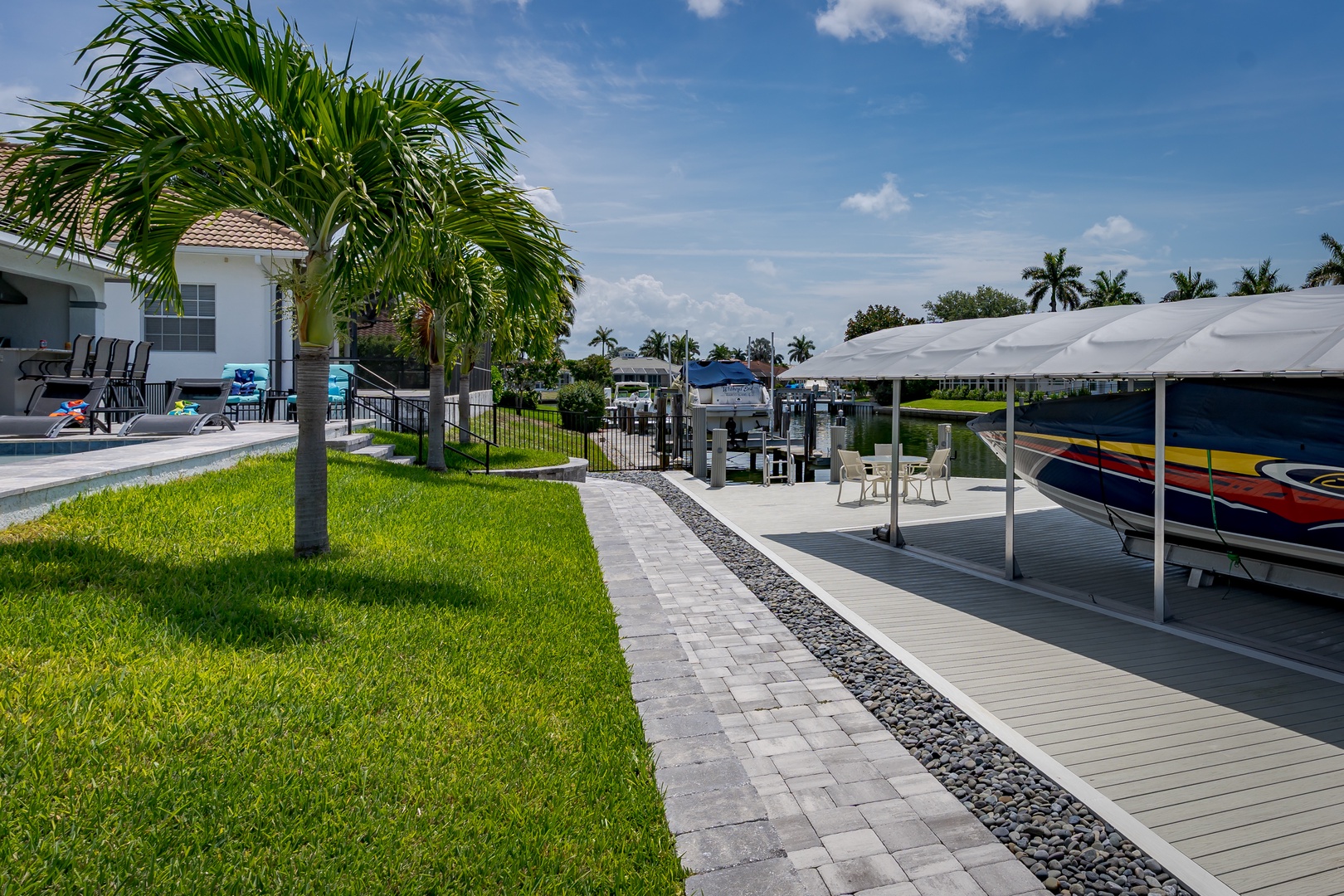 Waterfront property featuring a private boat dock with covered boat lift, lush tropical landscaping, and direct canal access perfect for boating enthusiasts exploring the area.