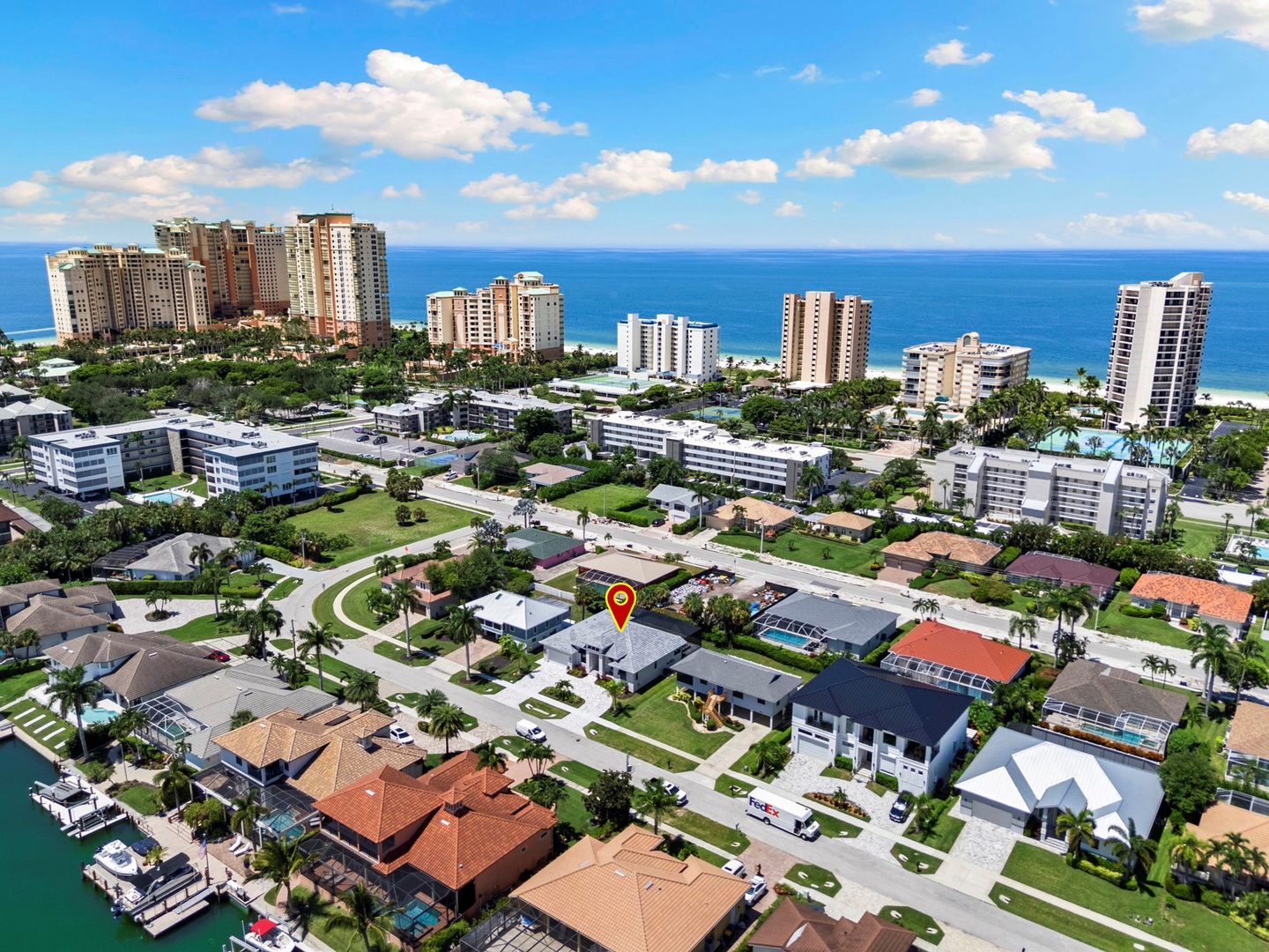 An aerial view of a residential neighborhood located just moments from the beach, nestled between coastal high-rises and the sparkling ocean beyond.