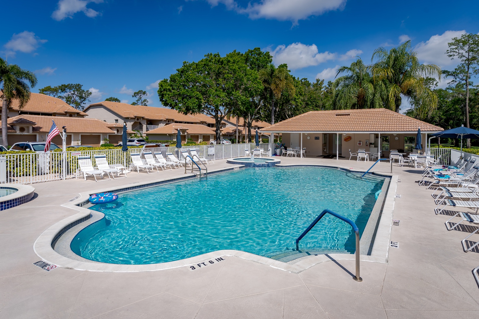 Sparkling community pool surrounded by comfortable loungers and lush tropical landscaping, perfect for sunny afternoon swims or relaxing poolside under the Florida sky.