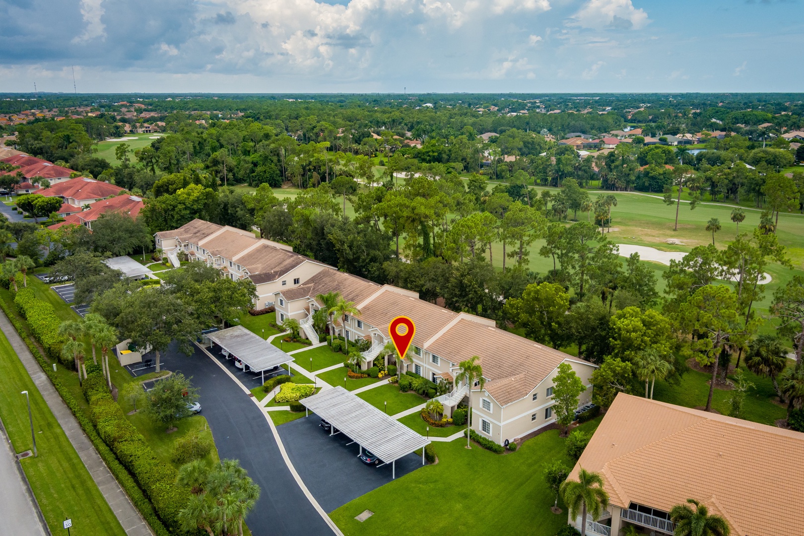 Aerial view of the property nestled within a lush, tree-lined neighborhood adjacent to golf course greens and residential communities.