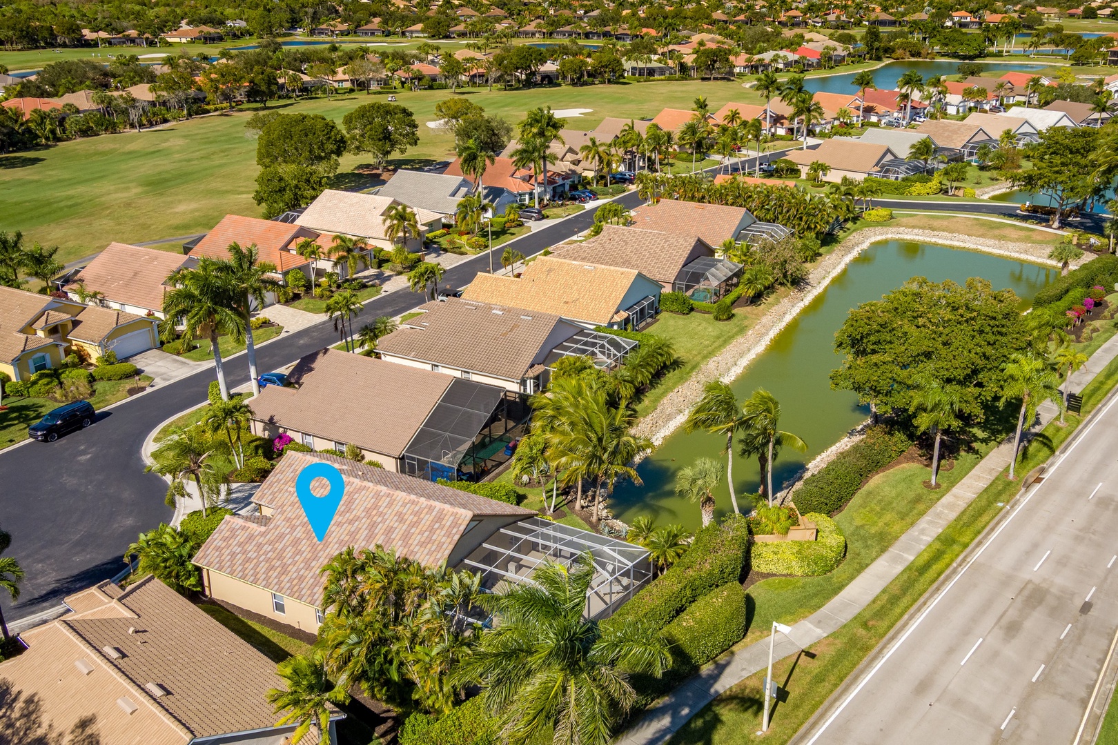 Aerial view of a residential neighborhood featuring homes with tile roofs, tropical landscaping, and recreational amenities including a golf course.