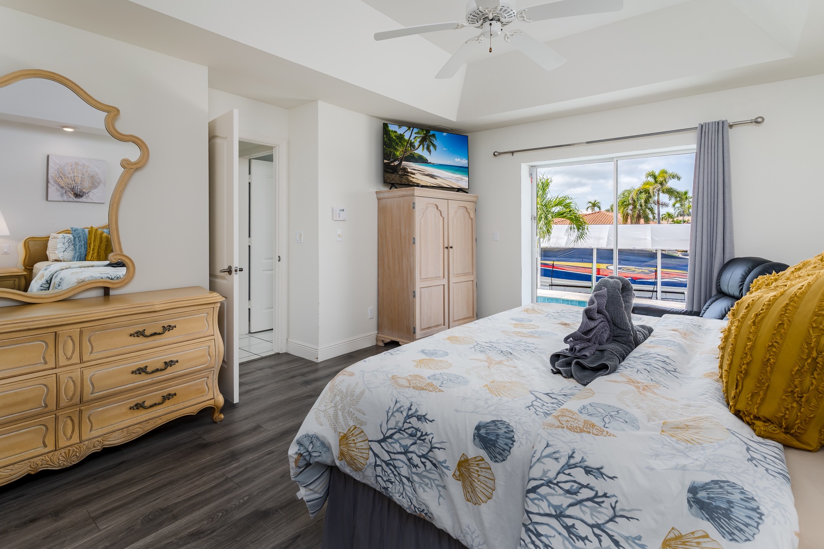 Unwind in this coastal-inspired bedroom where coastal charm meets comfort. Slip into soft linens adorned with seashell motifs and enjoy tropical pool views framed by swaying palms just beyond your private sliding door.
