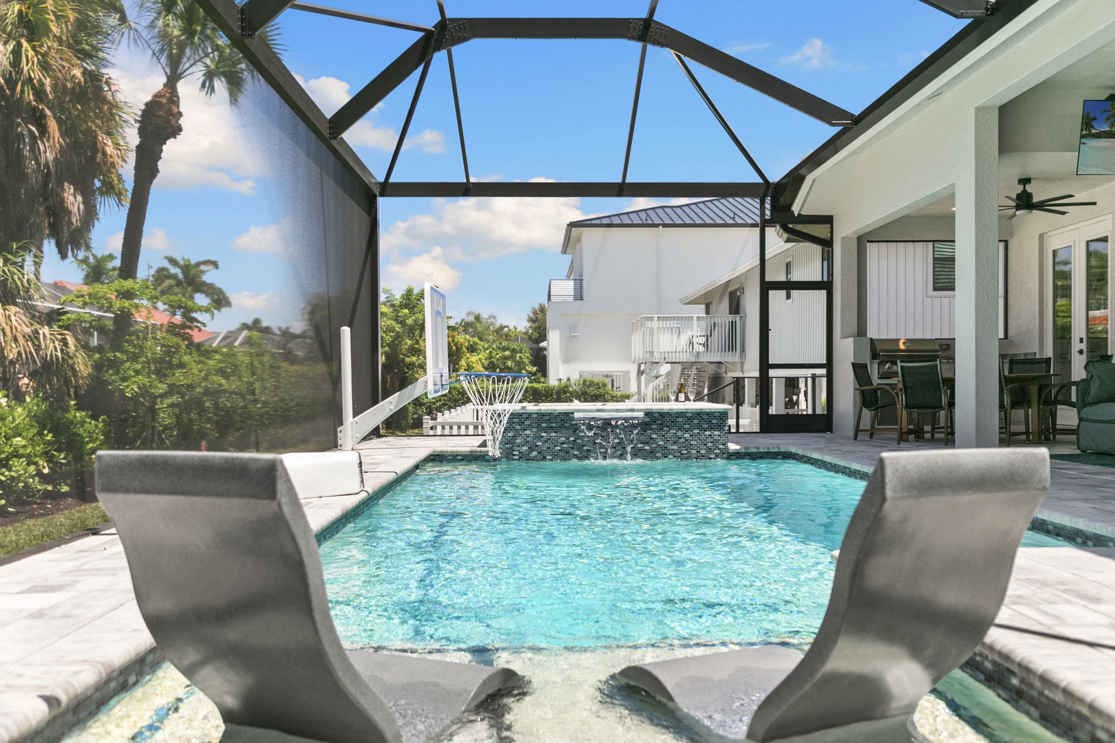 Your private oasis awaits — lounge on these in-pool chairs, play a game of poolside basketball, or simply relax beneath the screened enclosure while sunshine spills through overhead.