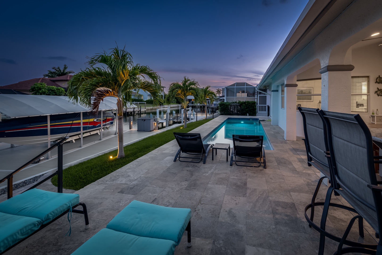 A modern waterfront home featuring a private pool, tropical palms, and boat dock access—ideal for sunset views and waterside relaxation.