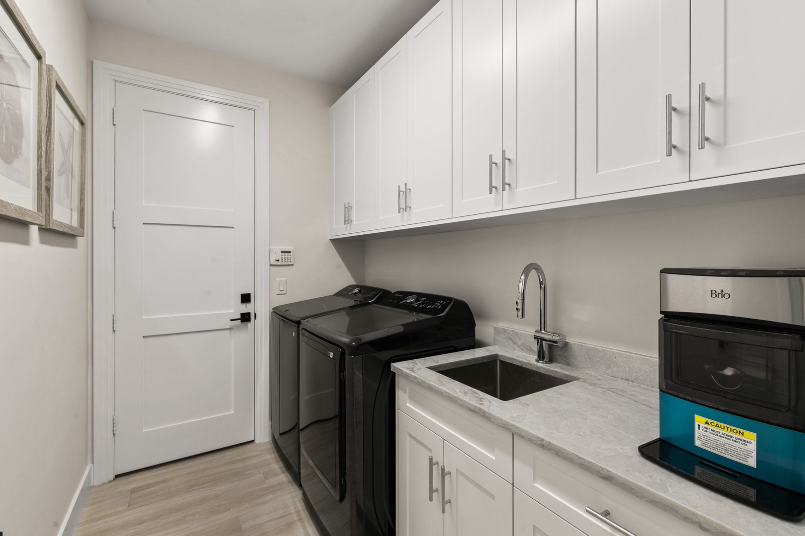 Your dedicated laundry room combines function and style with a modern washer and dryer, a deep sink for easy prep, and crisp white cabinetry offering plenty of storage.