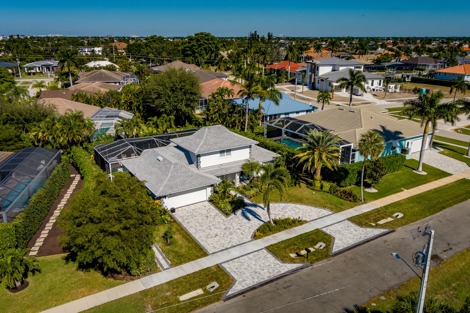 Aerial view of a peaceful residential neighborhood with palm-lined streets and tropical landscaping in a sunny Florida setting.