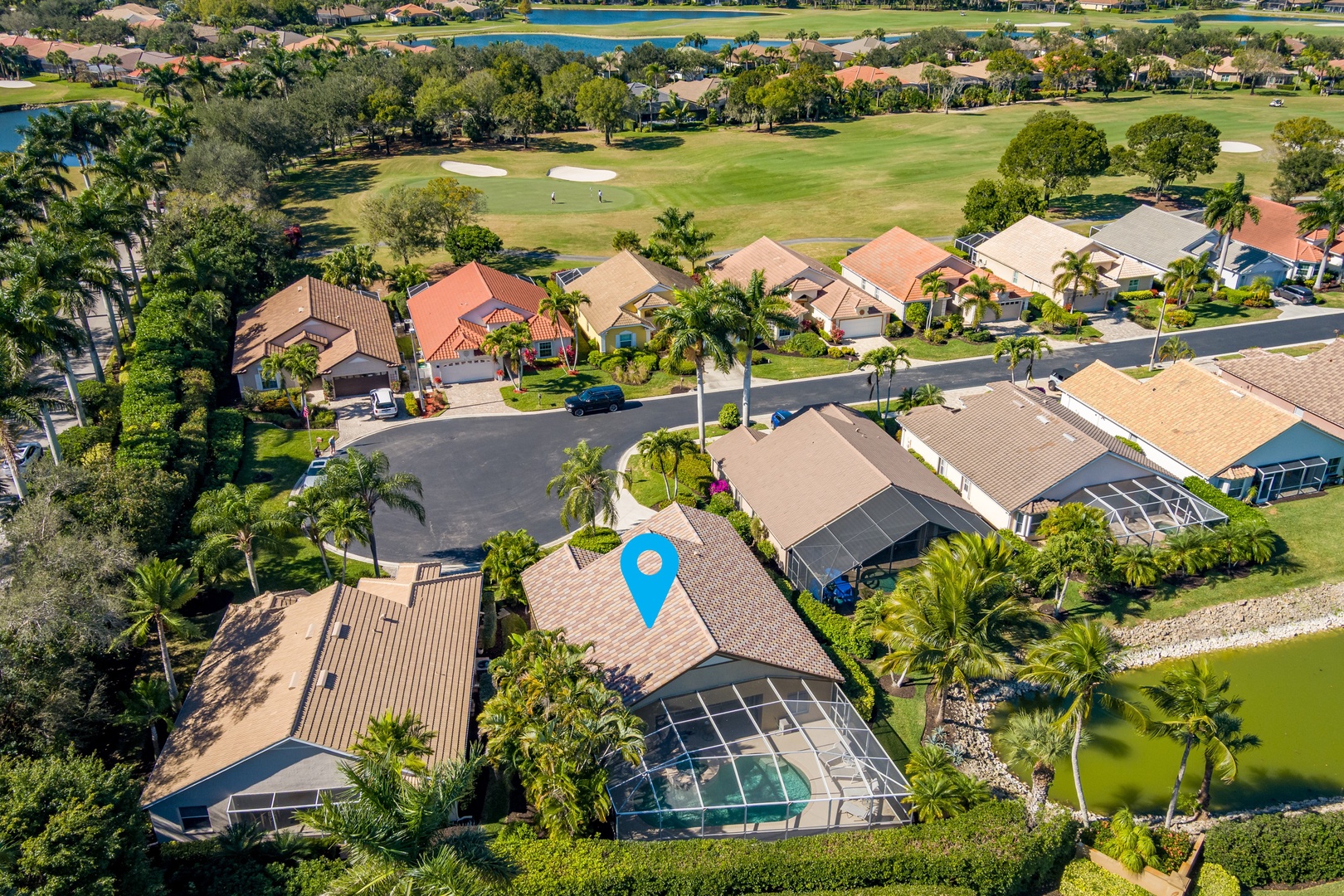 Aerial view of an upscale residential neighborhood featuring golf course frontage, tropical landscaping, and waterfront proximity in a peaceful Florida community setting.