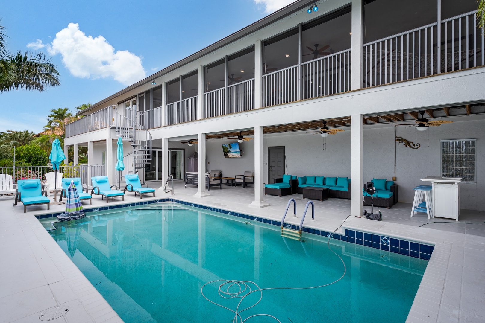 Your private oasis awaits with a sparkling pool, covered lounge with turquoise seating, and upstairs balcony access—perfect for soaking up sunny days and relaxing evenings.