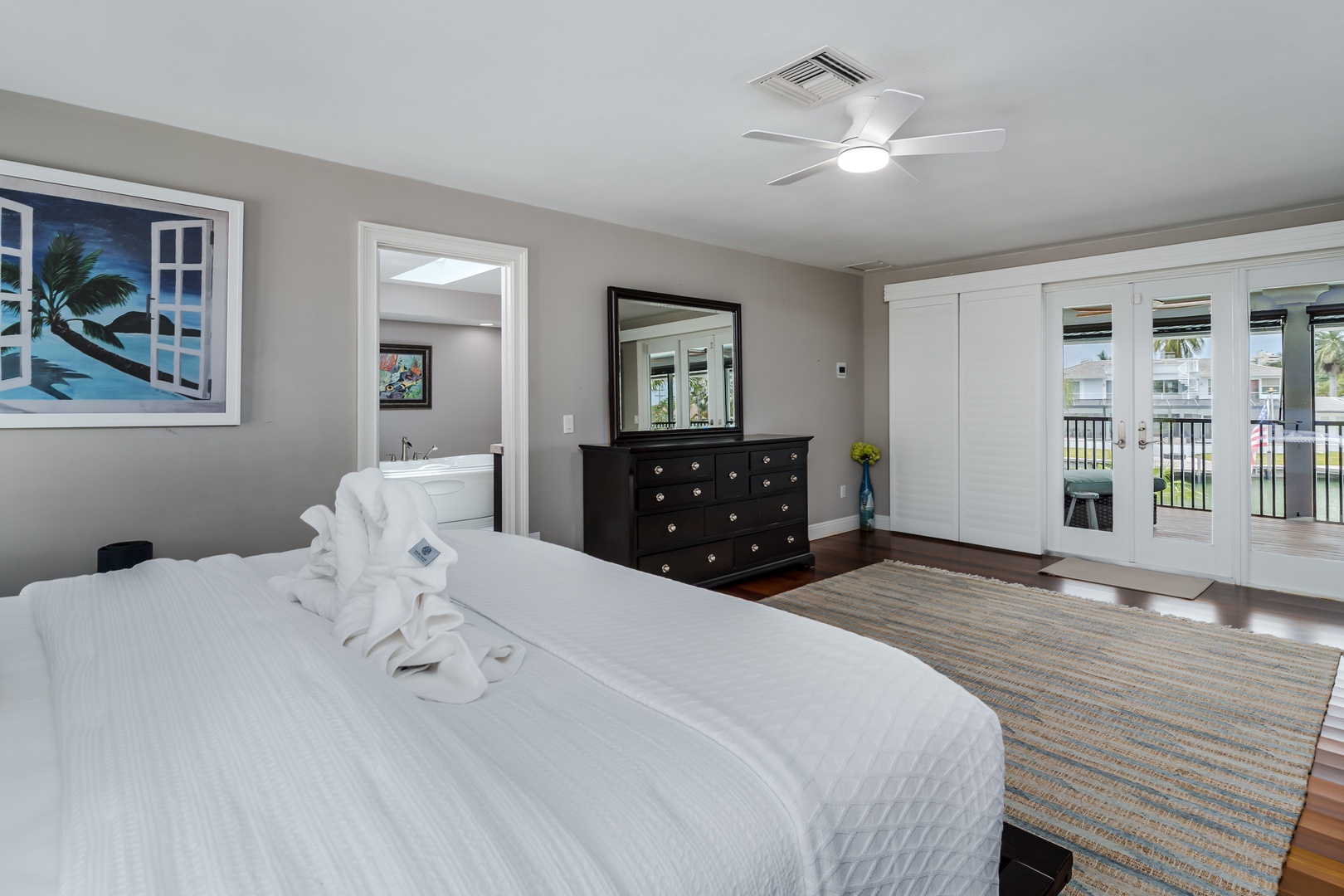 Wake up to serene waterfront views through your private balcony doors, then sink into crisp white linens on your plush bed. Ceiling fans and coastal-inspired artwork complete your peaceful retreat with plenty of storage in elegant wardrobes.