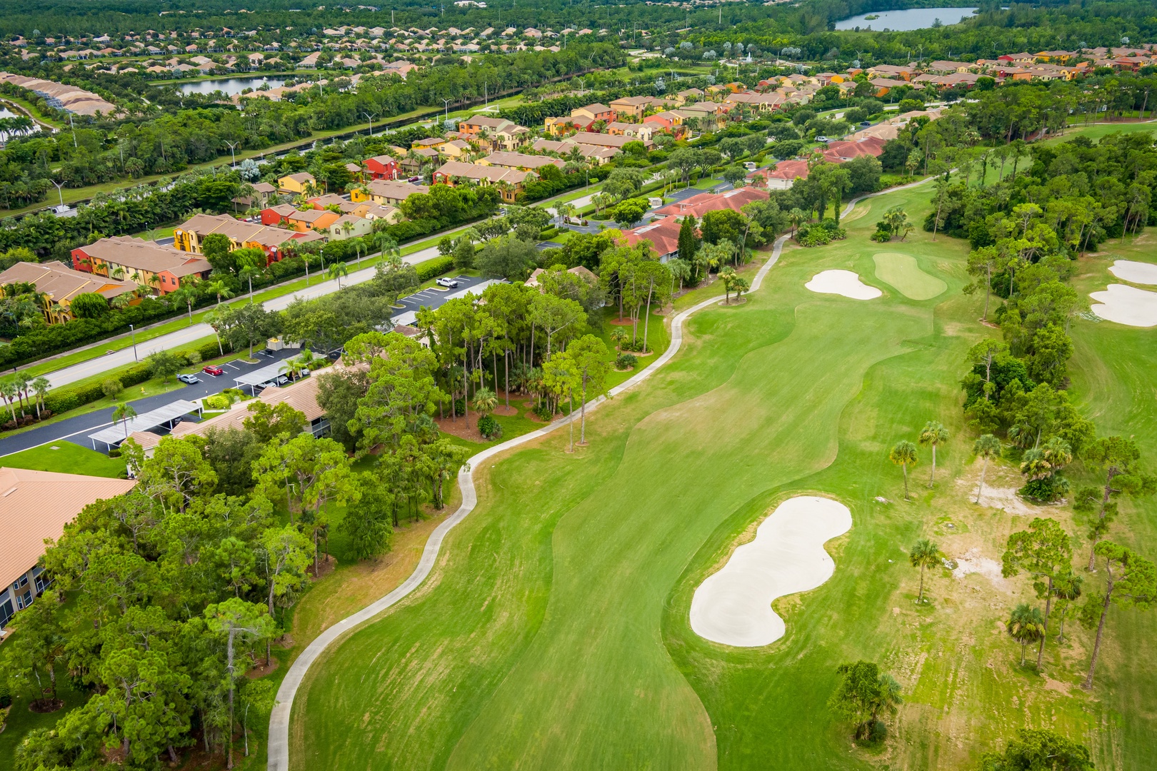Aerial view of the property nestled within a lush golf course community, surrounded by pristine fairways, tropical trees, and scenic waterways.