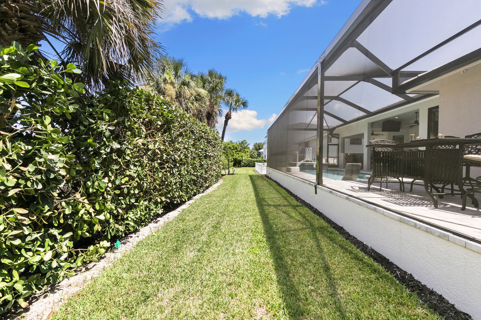 Enjoy your private screened outdoor space with lush greenery and tropical landscaping on a sunny day. Perfect for relaxing by the pool or dining al fresco in peaceful Florida surroundings.