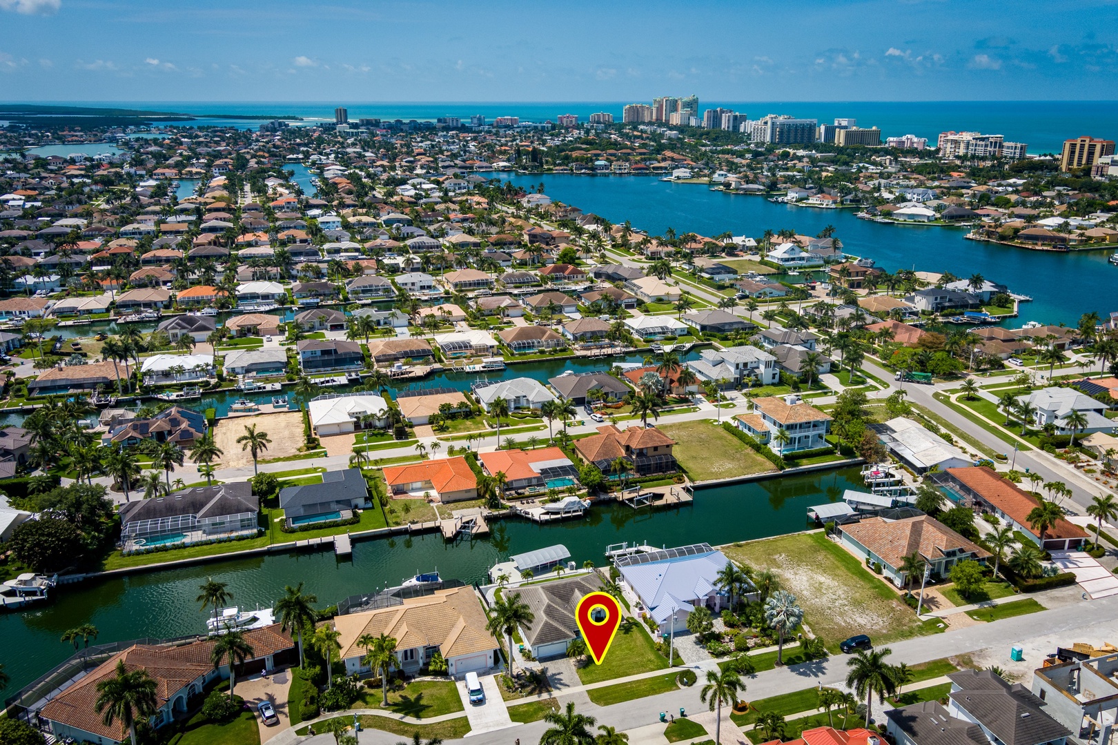 Aerial view of a waterfront neighborhood with canal-front homes, boat docks, and ocean access in a coastal Florida community.