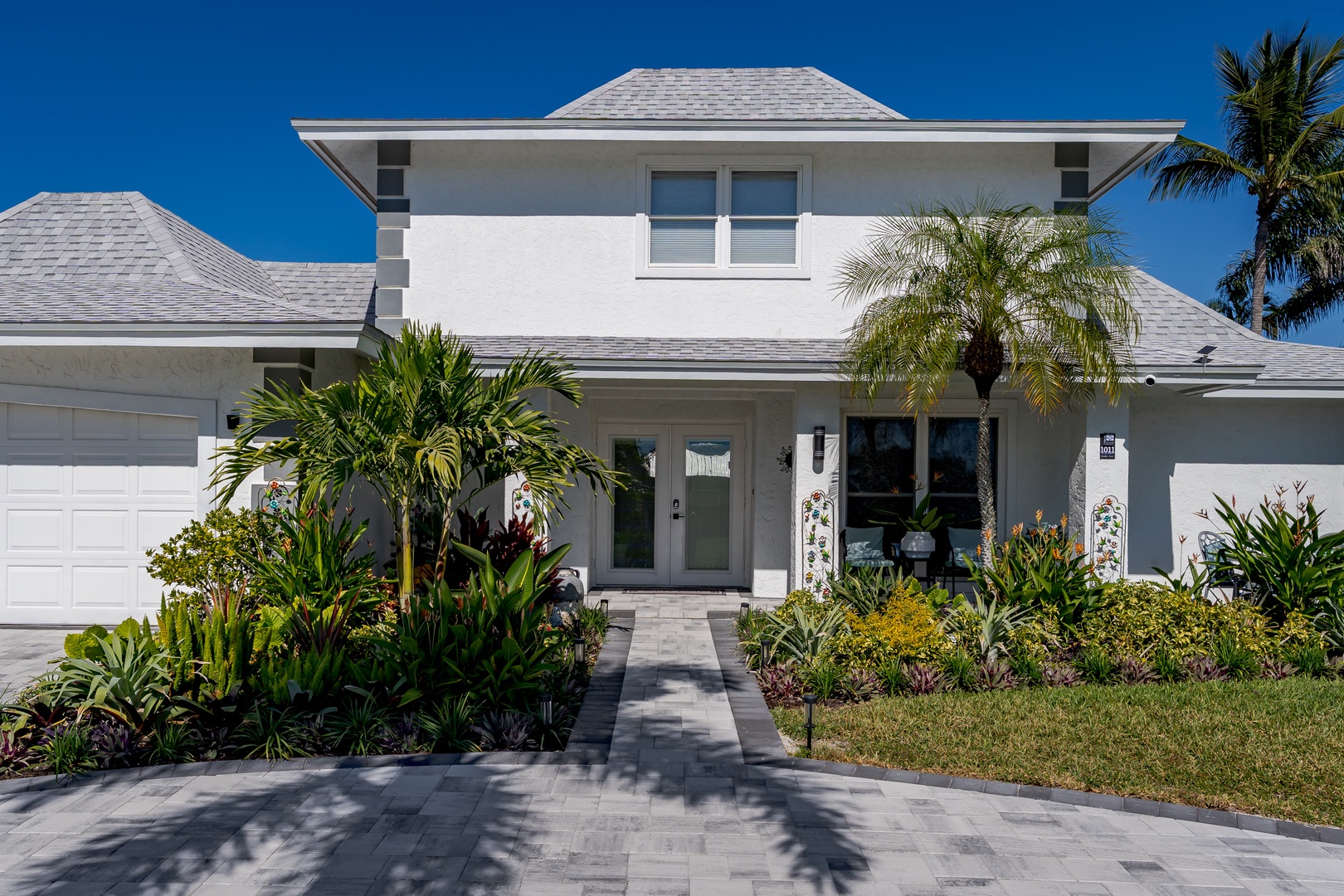 Modern tropical home with lush palm landscaping and elegant stonework entrance.