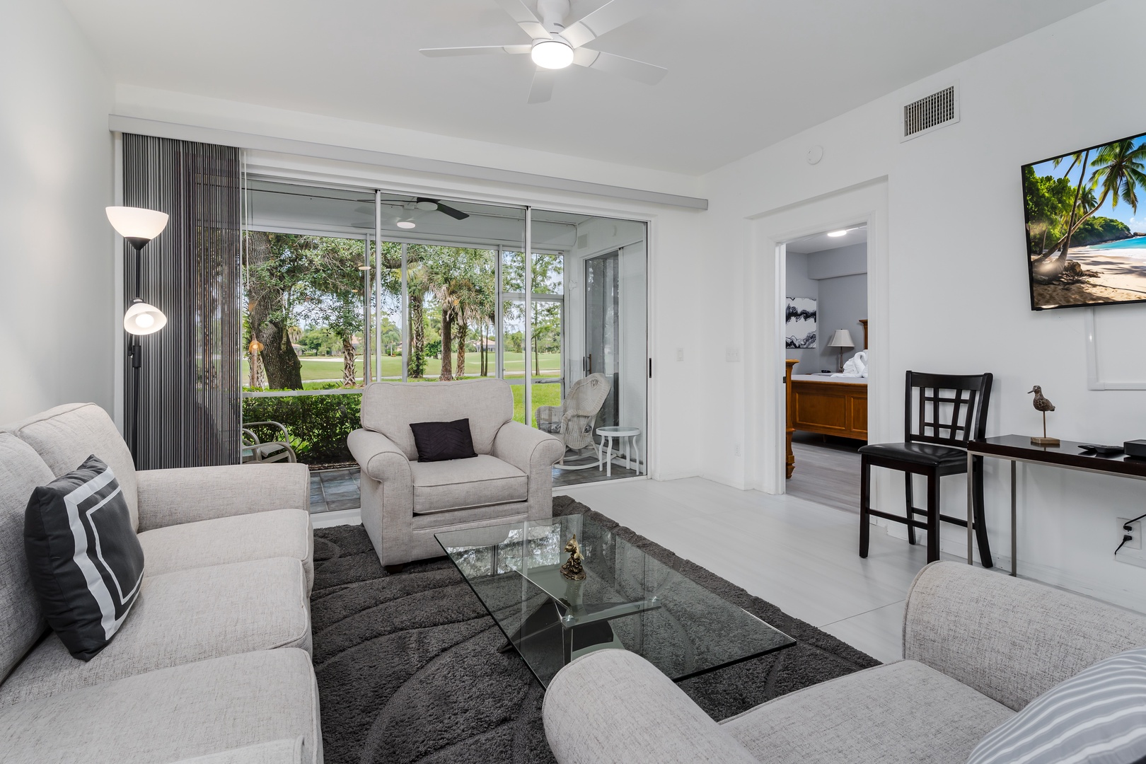 Sink into plush seating as natural light floods through expansive glass doors, opening your retreat to peaceful greenery beyond—an inviting haven where comfort meets tranquility.