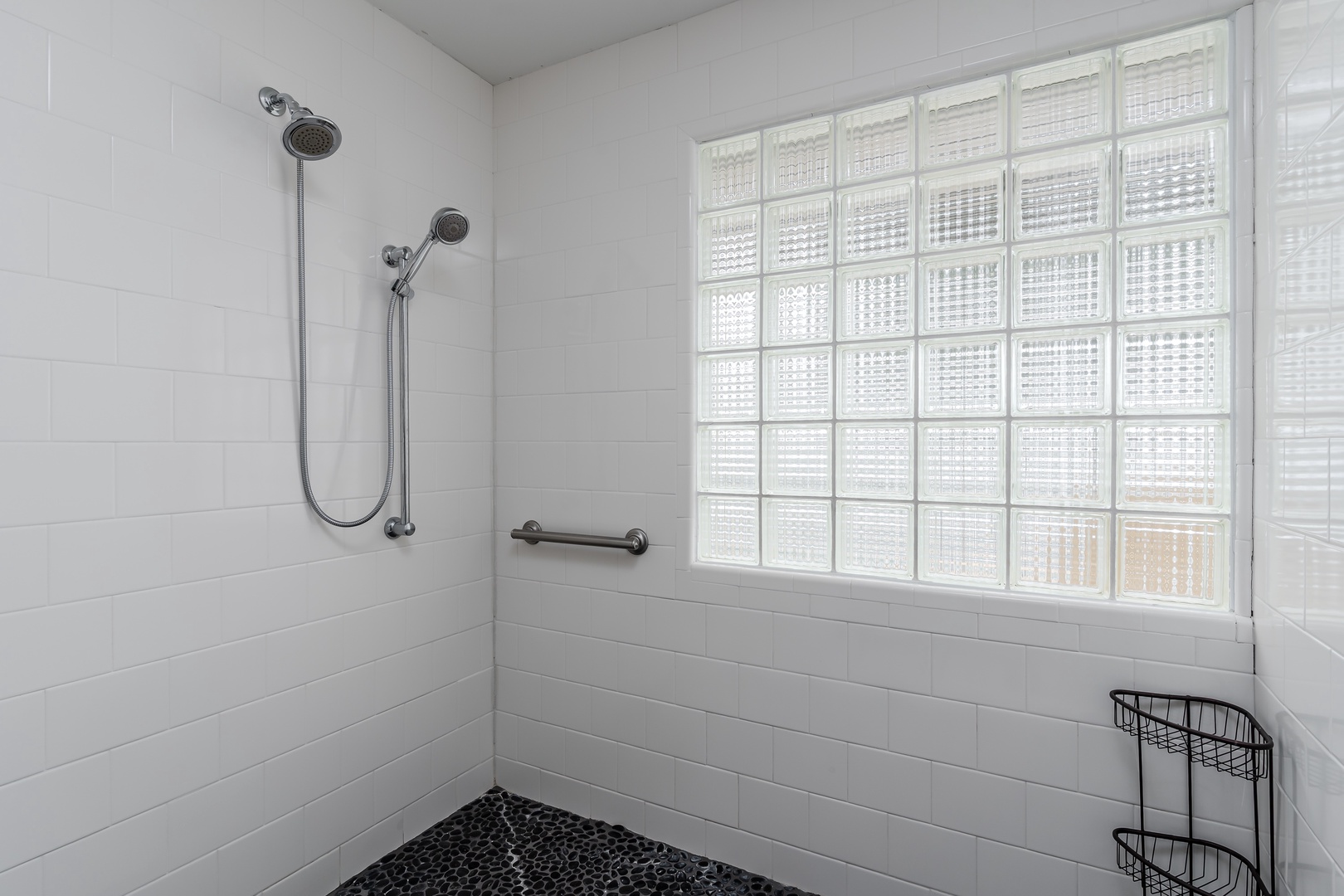 Step into your spacious walk-in shower with dual showerheads and a rainfall option—an accessible, bright sanctuary where glass block windows let in natural light while maintaining privacy.