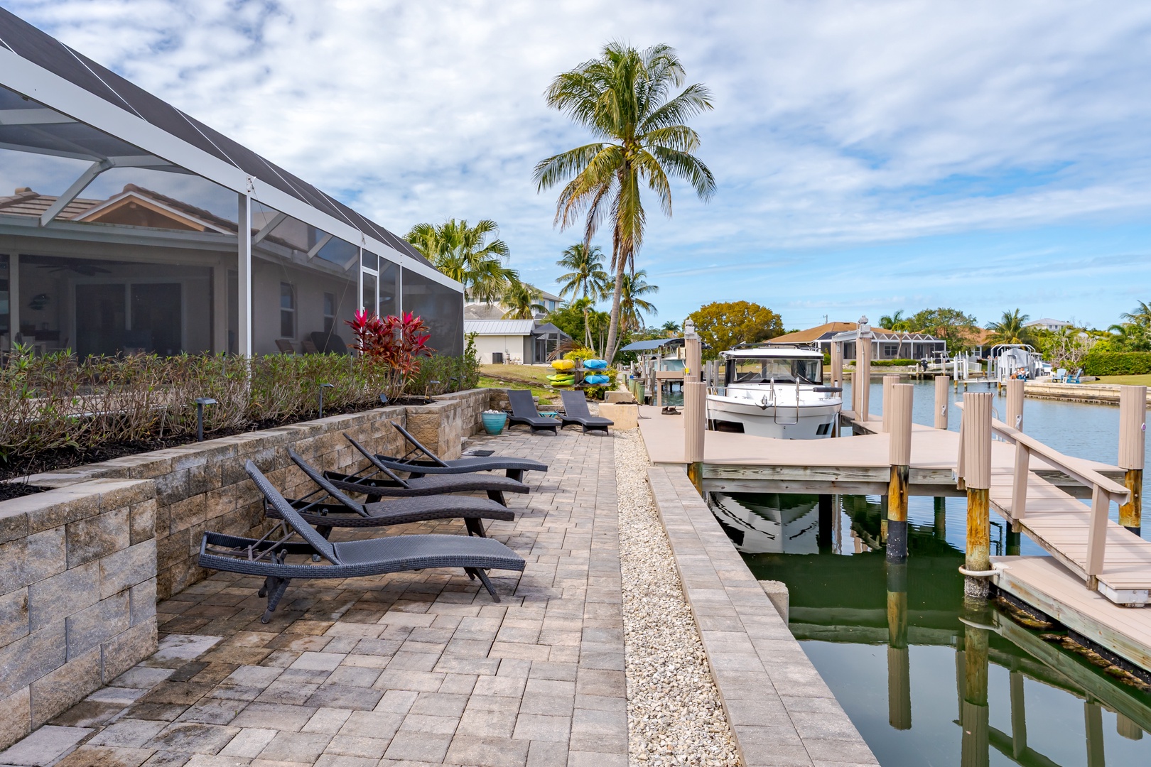 Picture your perfect waterfront escape with loungers beside your private dock, where tropical palms frame endless blue skies and gentle waters await.