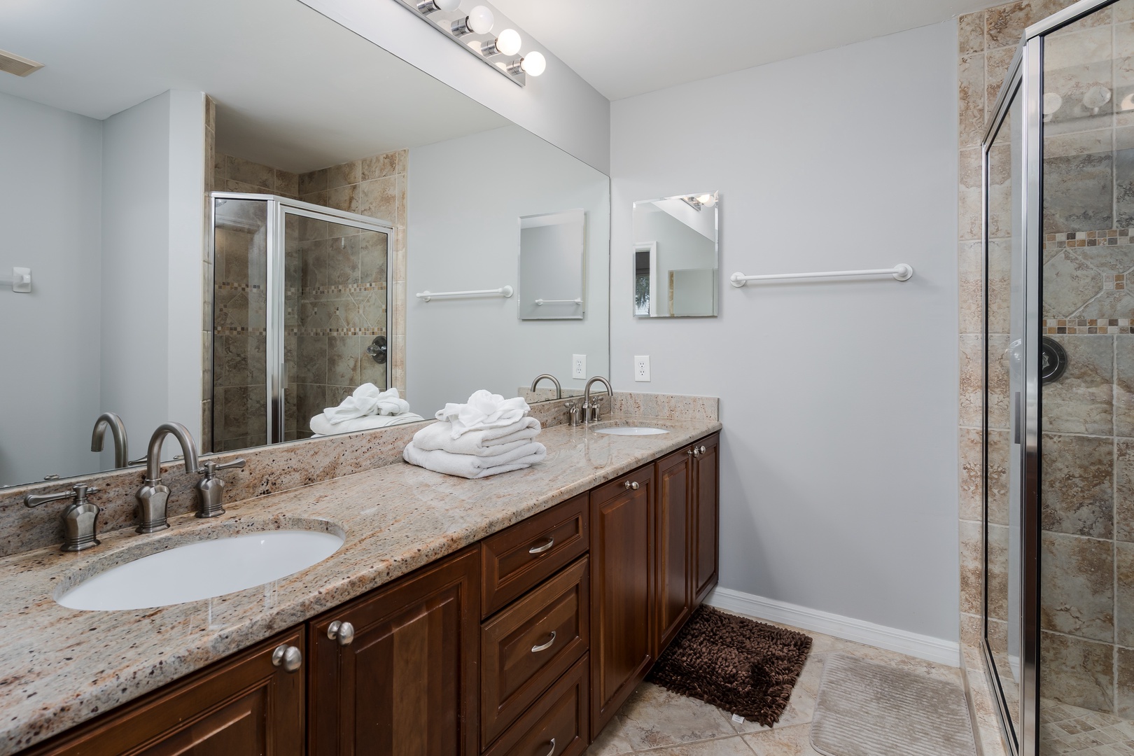 Refresh in your elegant dual-sink bathroom, where granite counters, plush white towels, and a stunning walk-in shower await to elevate your daily routine.