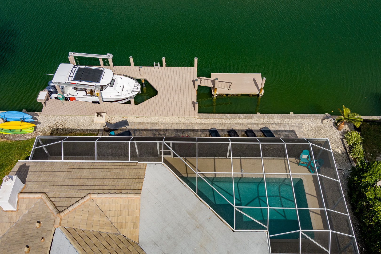 Aerial view of waterfront property featuring swimming pool, private dock with boat, and direct water access for the ultimate lakeside getaway.