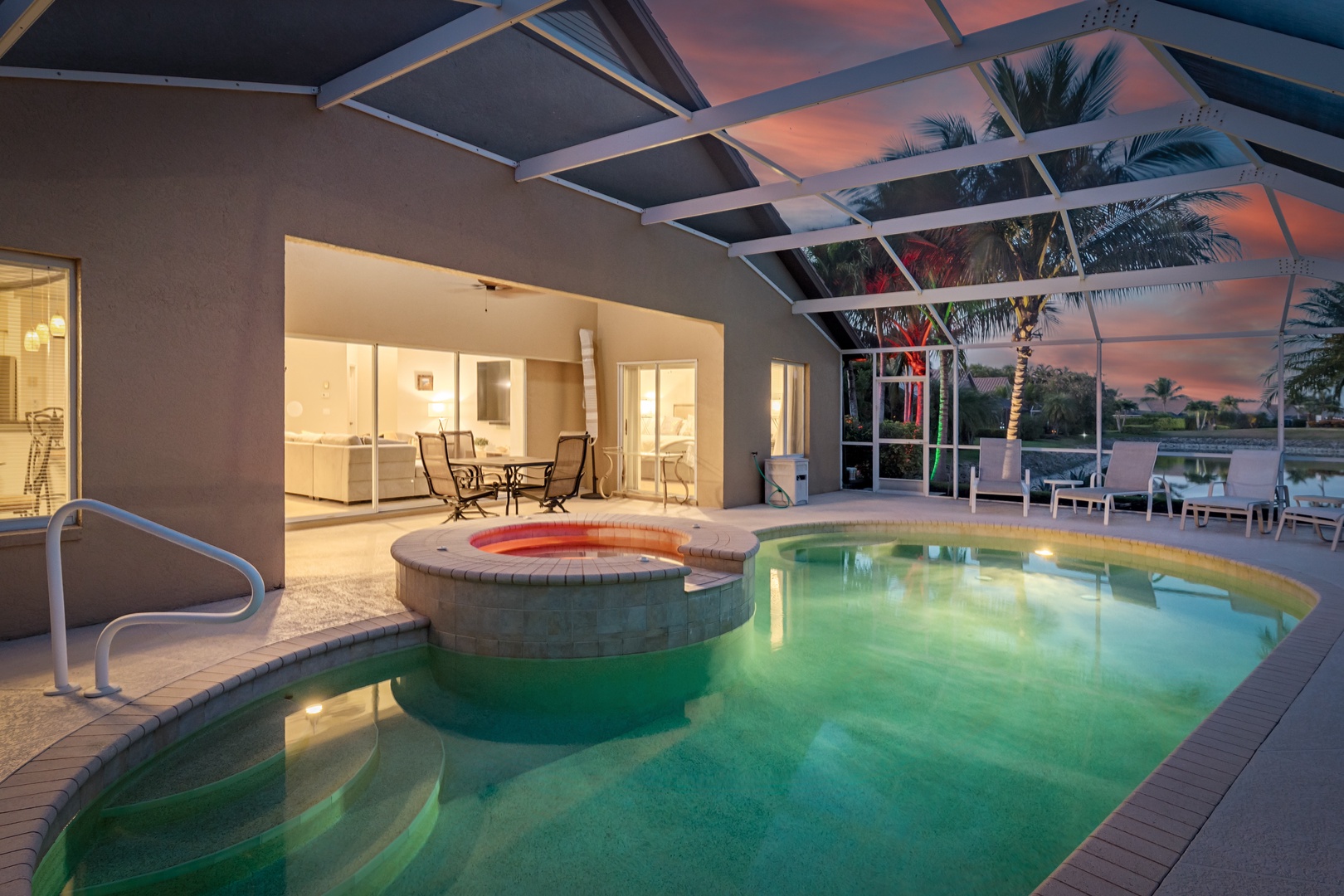 Unwind in your private screened pool oasis, where warm waters glow beneath a stunning sunset sky and tropical palms.