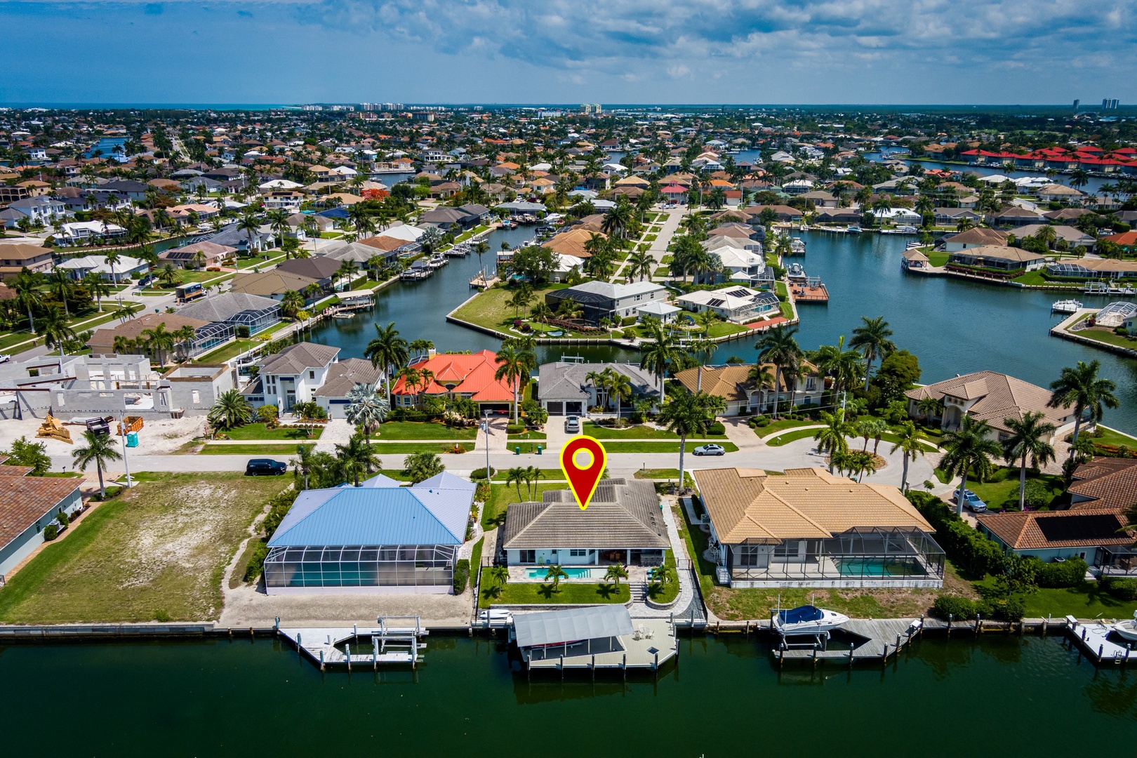Waterfront community featuring canal-front properties with private docks and boat access, located in a sunny coastal neighborhood with palm-lined streets.