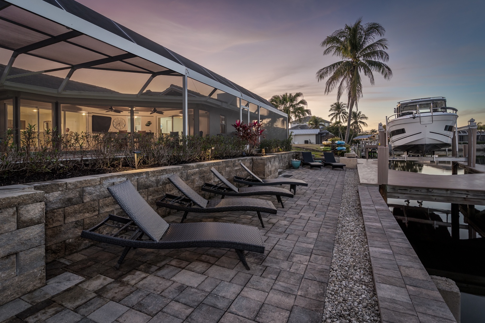 Waterfront paradise with private dock, lounge chairs under sunset skies, and palm trees framing your tropical escape.
