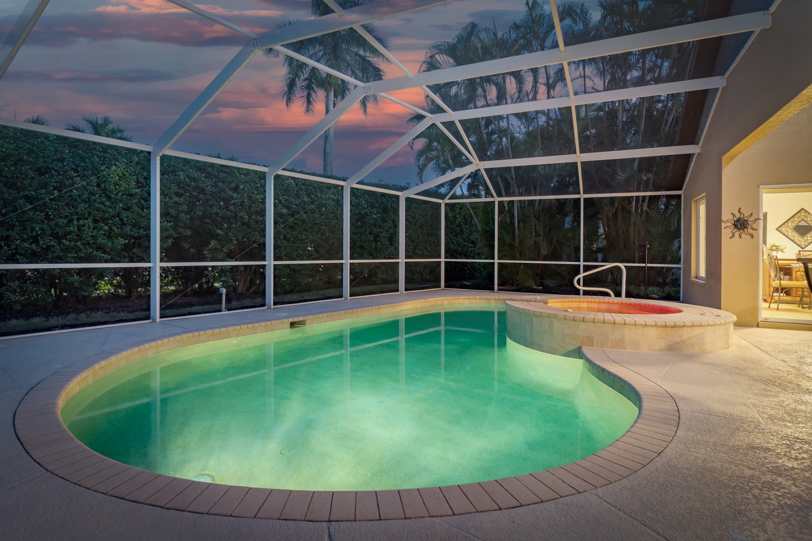 Your private screened pool glows invitingly at twilight, perfect for evening swims under the colorful sky.