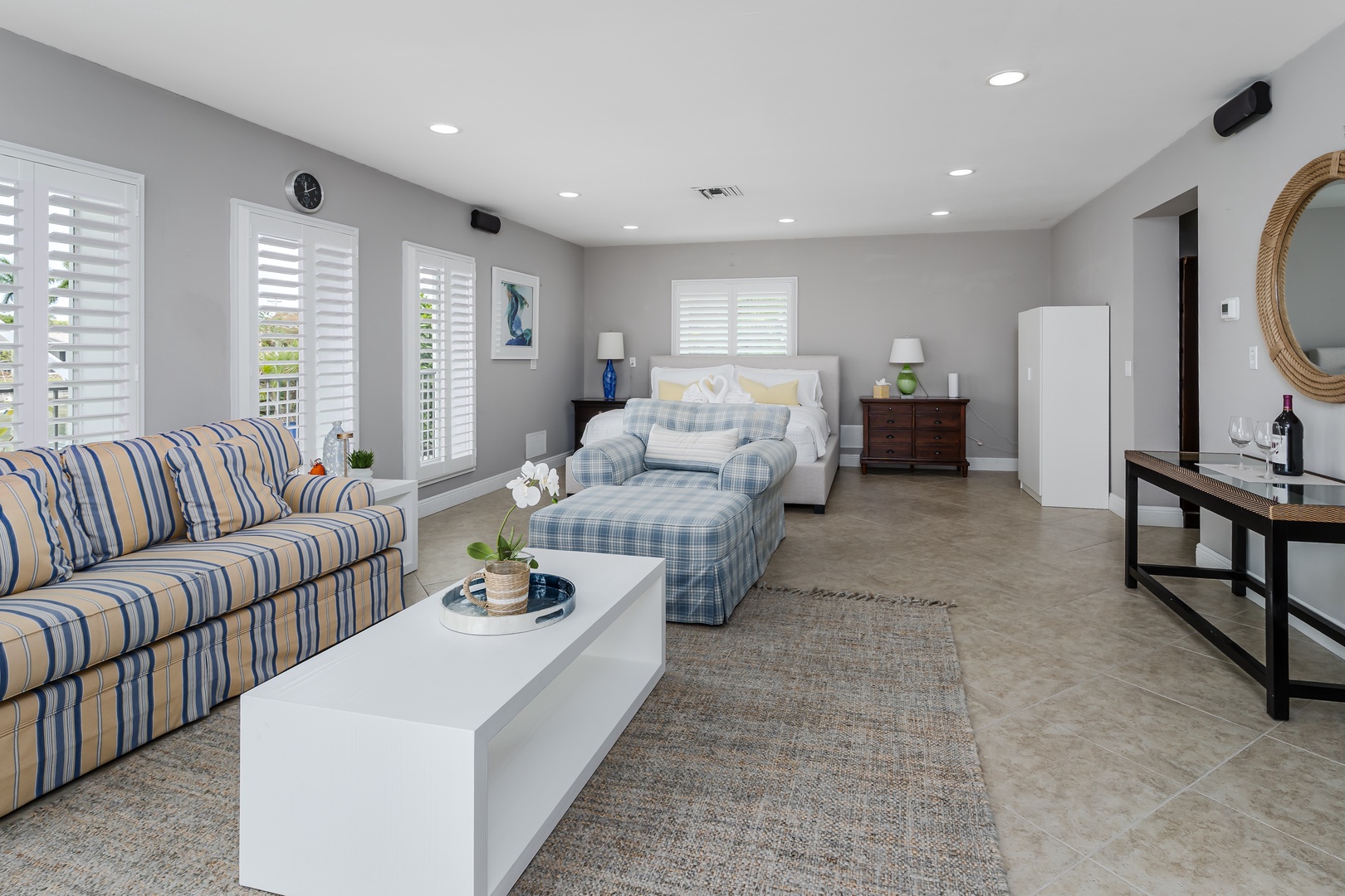Unwind in your serene bedroom suite, where coastal charm meets comfort. Sink into the plush chaise lounge, settle on your cozy bed, and enjoy soft natural light streaming through plantation shutters.
