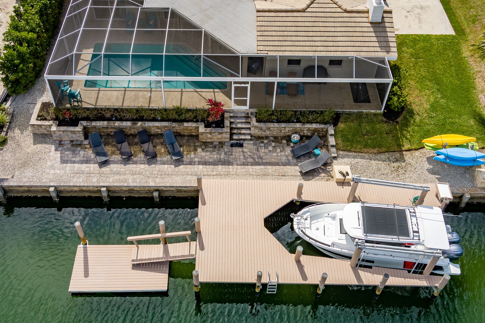 Aerial view of waterfront property featuring screened pool area, private dock with boat access, and outdoor entertaining spaces.