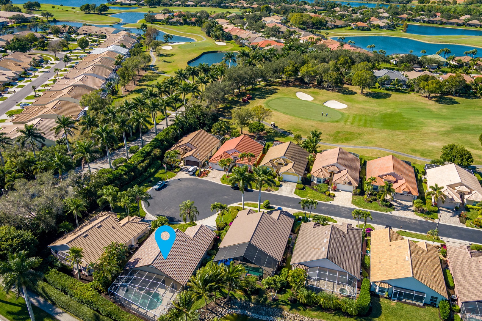 Golf course community with homes featuring screened pools, tropical landscaping, and scenic water views throughout the neighborhood.