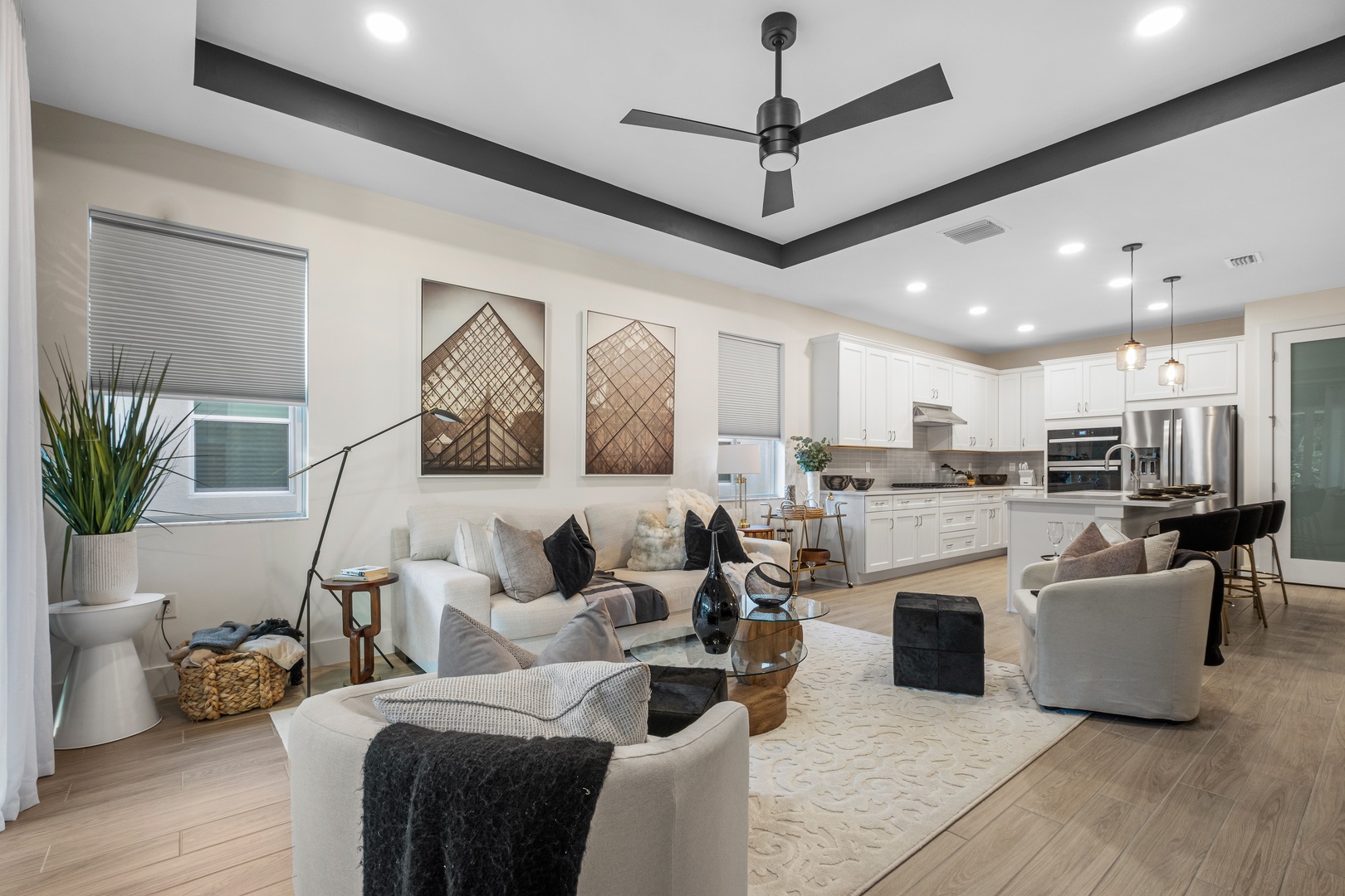 Relax in this stylish open-plan living space where comfort meets elegance, featuring plush seating and sleek kitchen access.