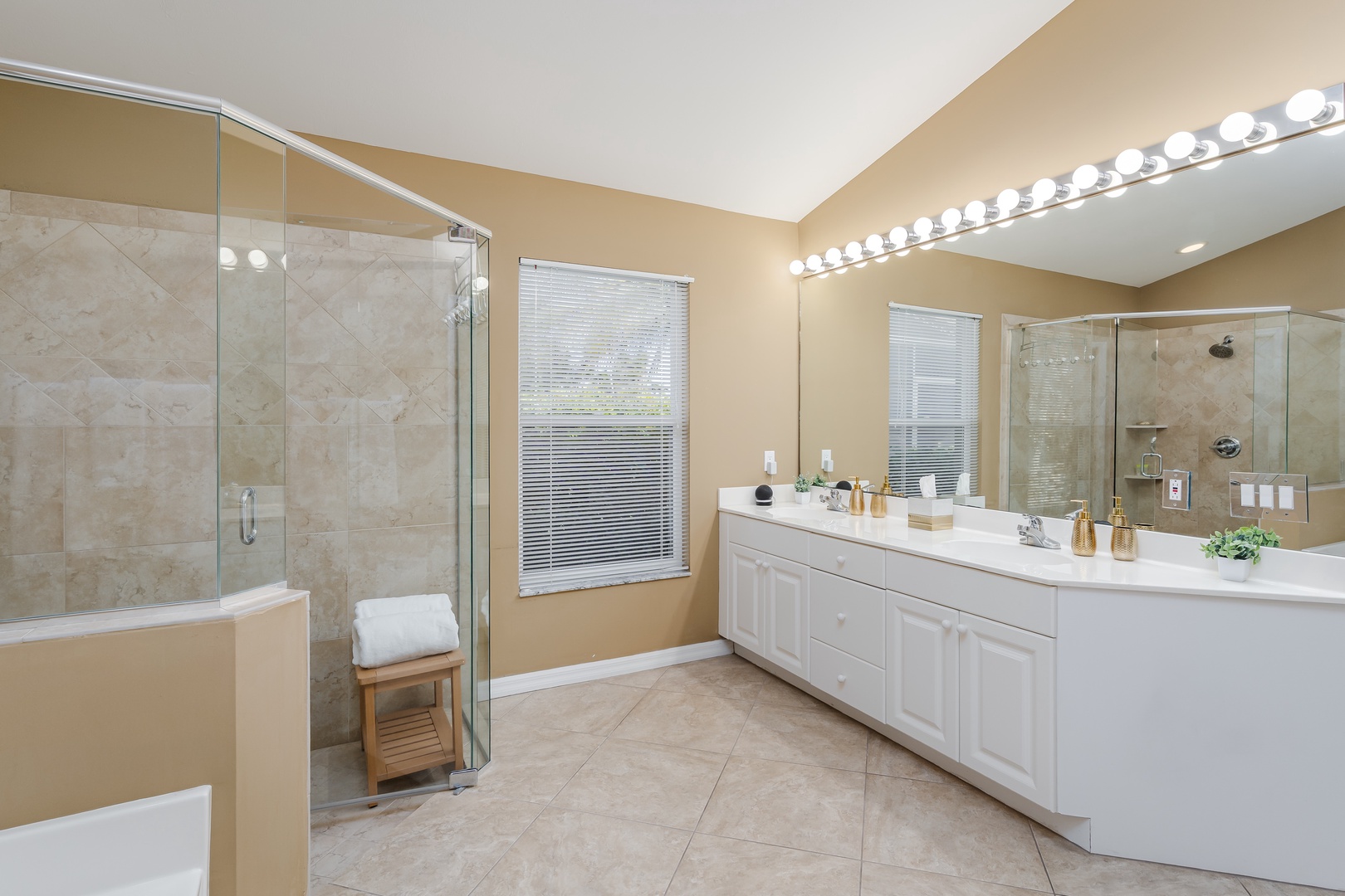 Step into your elegant spa-like bathroom with marble shower, dual vanity, and Hollywood-style lighting for your perfect morning routine.