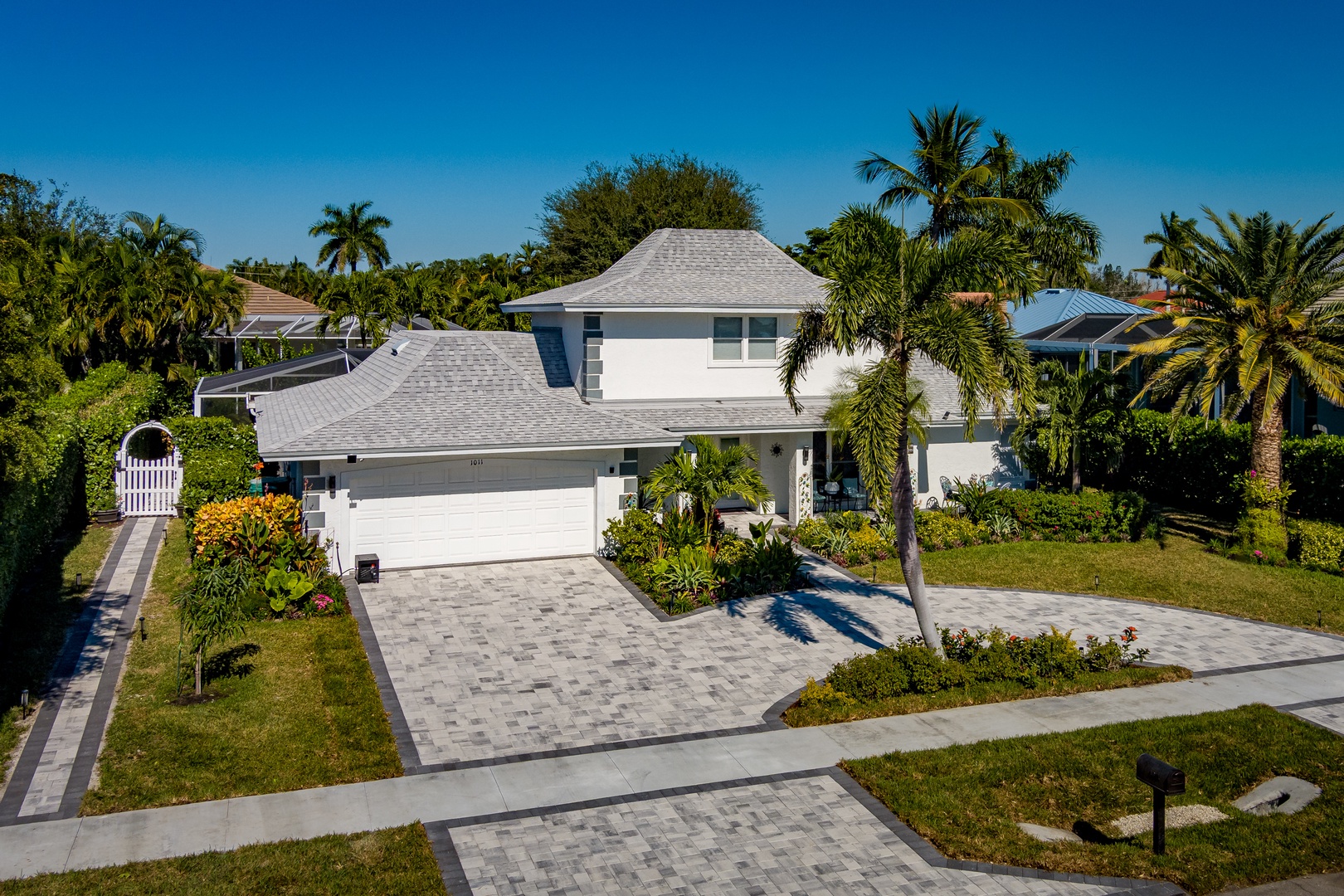 Stunning two-story vacation home surrounded by lush tropical palms and manicured gardens in a peaceful residential neighborhood.