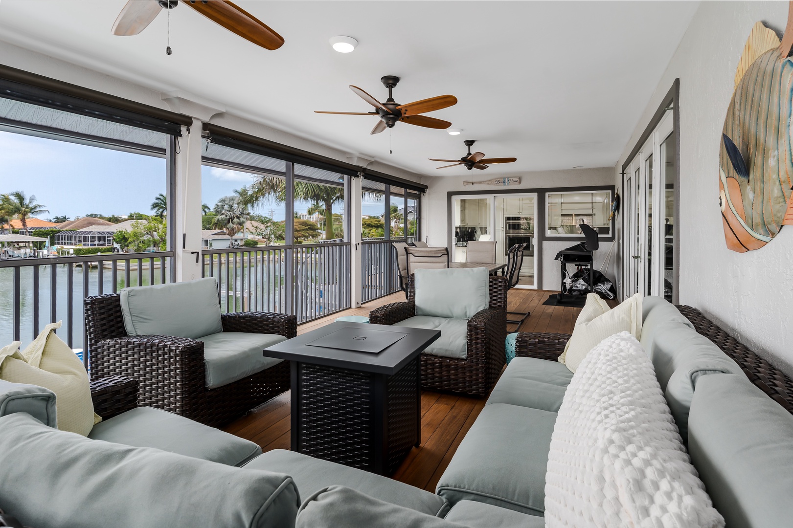Picture yourself lounging on plush outdoor seating, cooled by gentle ceiling fans, as you gaze across tranquil waterfront views framed by swaying palms—your private escape awaits.