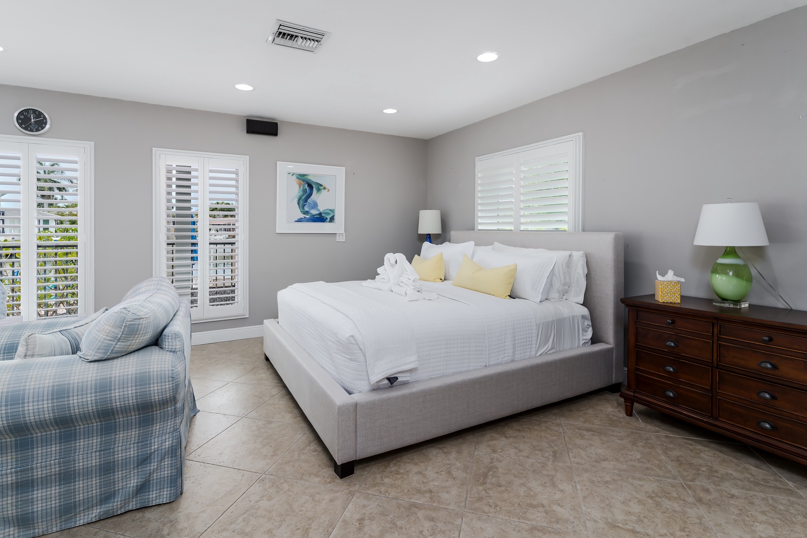 Sink into crisp white linens and plush pillows in your serene bedroom retreat, where soft grey walls and coastal artwork create a peaceful haven for restful nights.