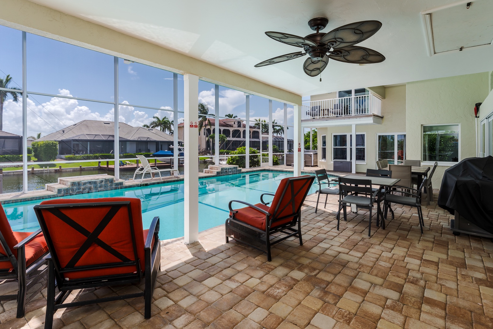 Relax in your screened patio with vibrant red seating overlooking the sparkling pool and waterfront views.