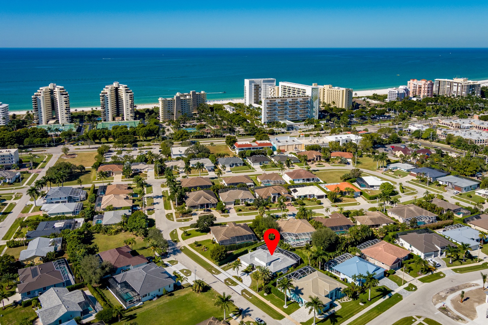 Aerial view of beachfront community with residential neighborhoods and high-rise buildings along pristine coastline.