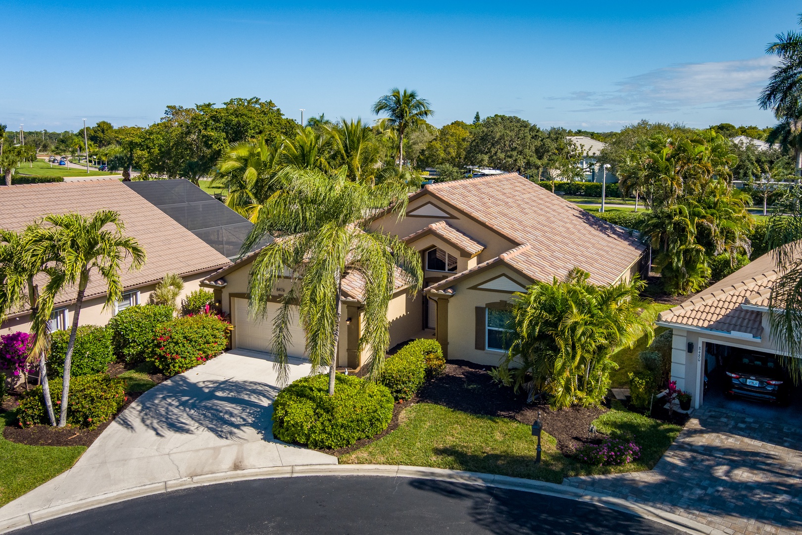Stunning aerial view of this tropical vacation home nestled in a lush Florida neighborhood with mature palm trees and manicured landscaping.