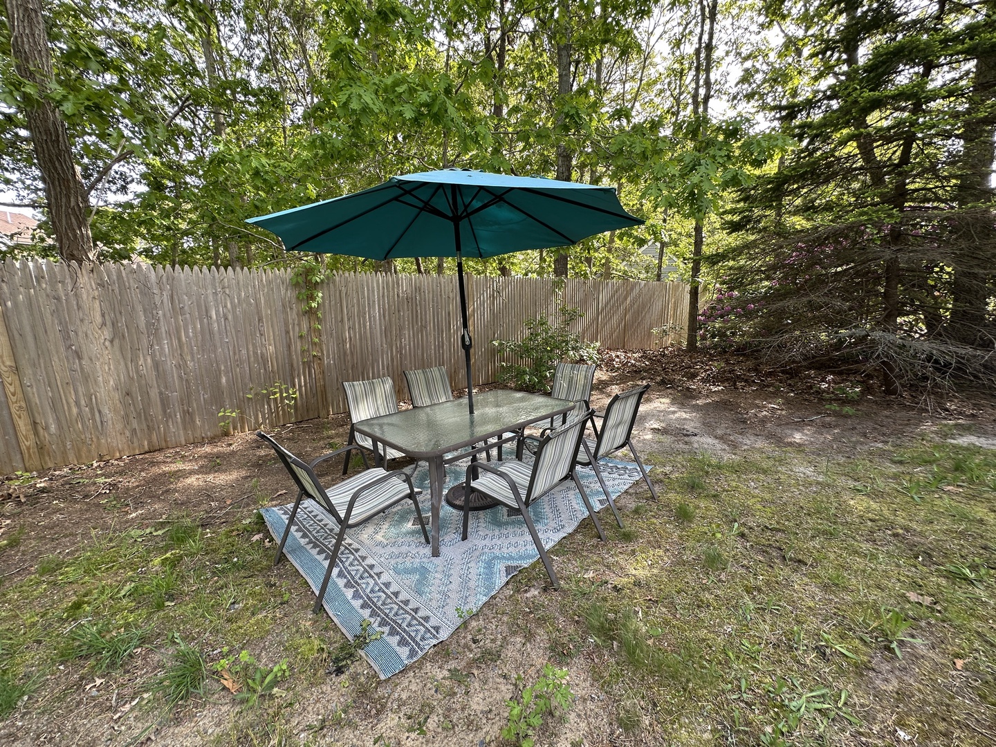 Enjoy alfresco meals under your private umbrella at this charming outdoor dining set, surrounded by peaceful trees and garden privacy.