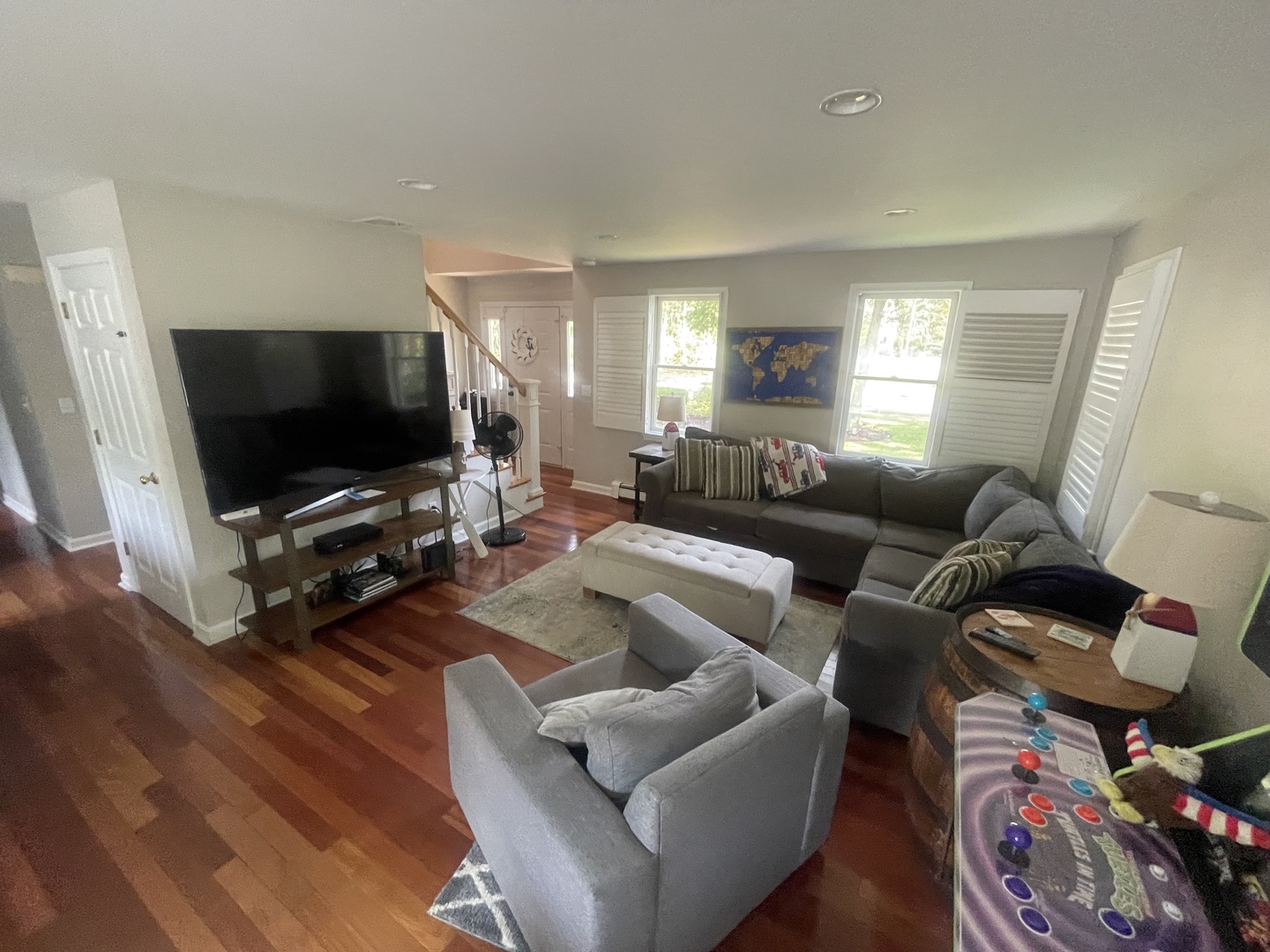 Gather with friends in your spacious living room featuring cozy gray sectionals, entertainment center, and warm hardwood floors perfect for relaxing evenings.