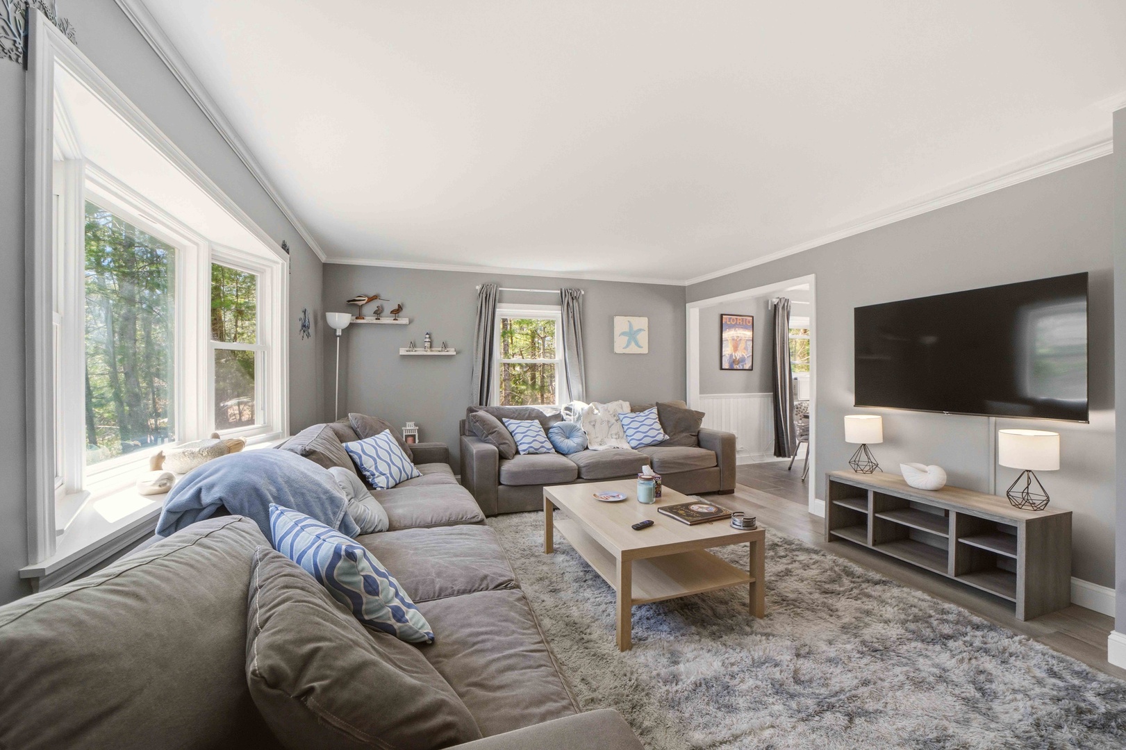 Sink into plush gray sofas while natural light streams through expansive windows. Your cozy retreat features a large TV for movie nights.