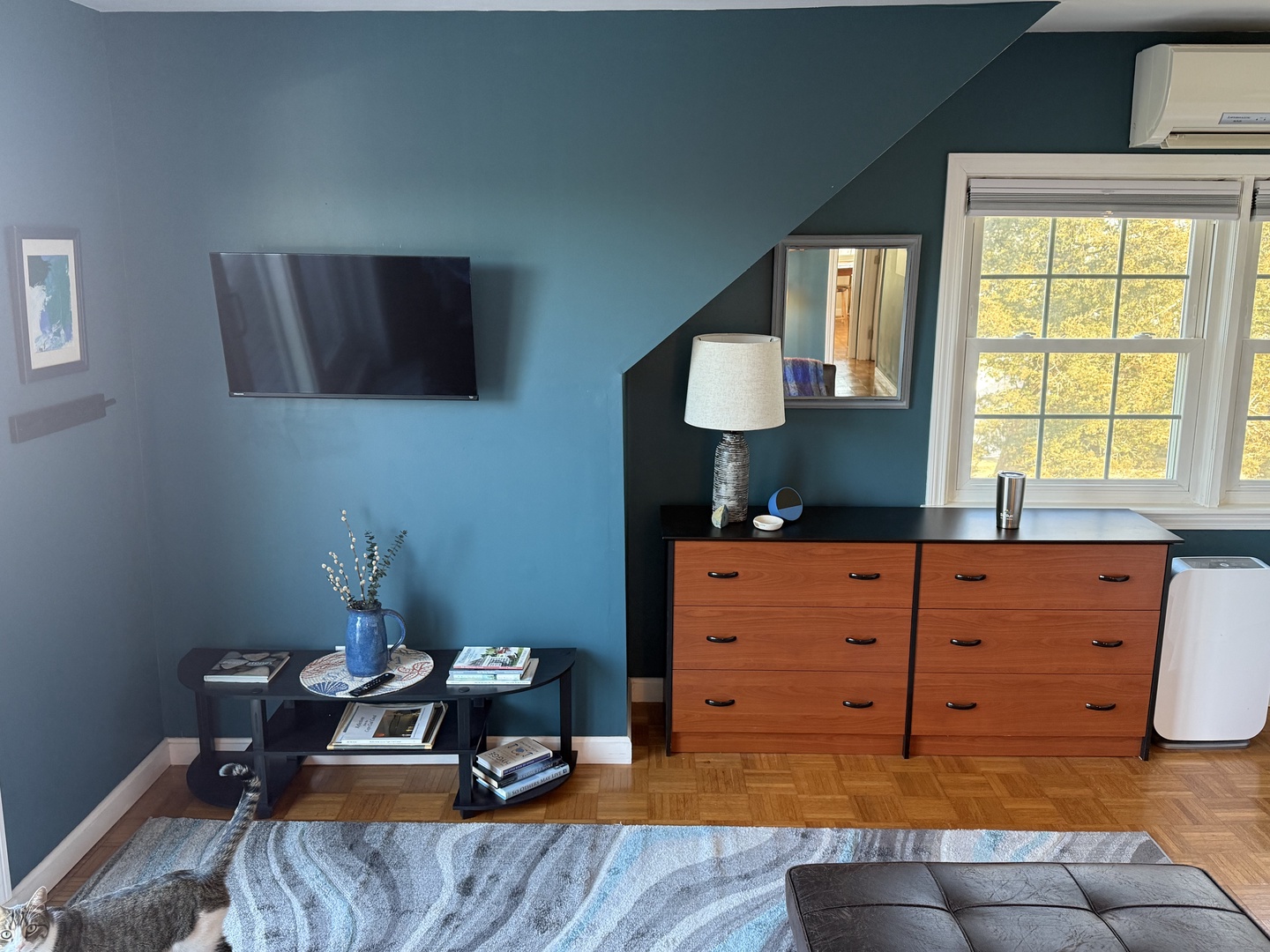 Relax in your stylish living space with rich teal walls, warm wood floors, and thoughtful touches throughout.