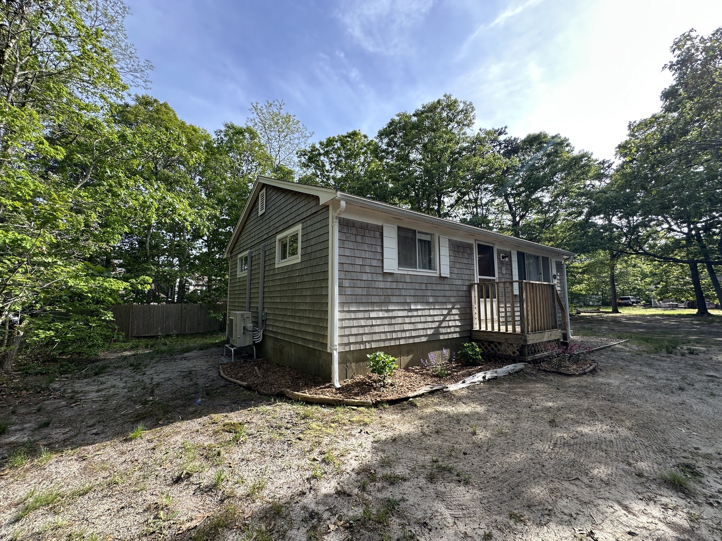 Charming cottage nestled among mature trees offers a peaceful woodland retreat with traditional cedar shingle siding and welcoming front porch.