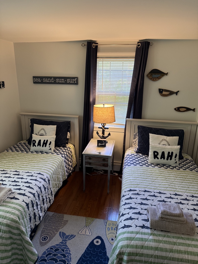 Your coastal retreat features matching twin beds with nautical-inspired bedding, soft lighting, and soothing beach-themed décor that brings the seaside indoors.
