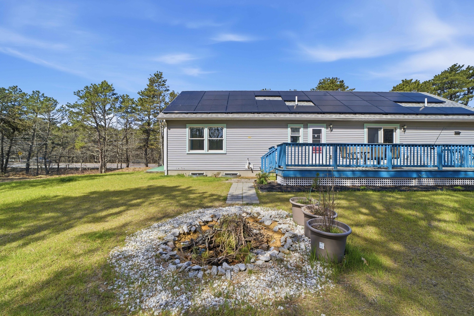 Modern home with solar panels sits on spacious grounds surrounded by mature trees and natural landscaping.