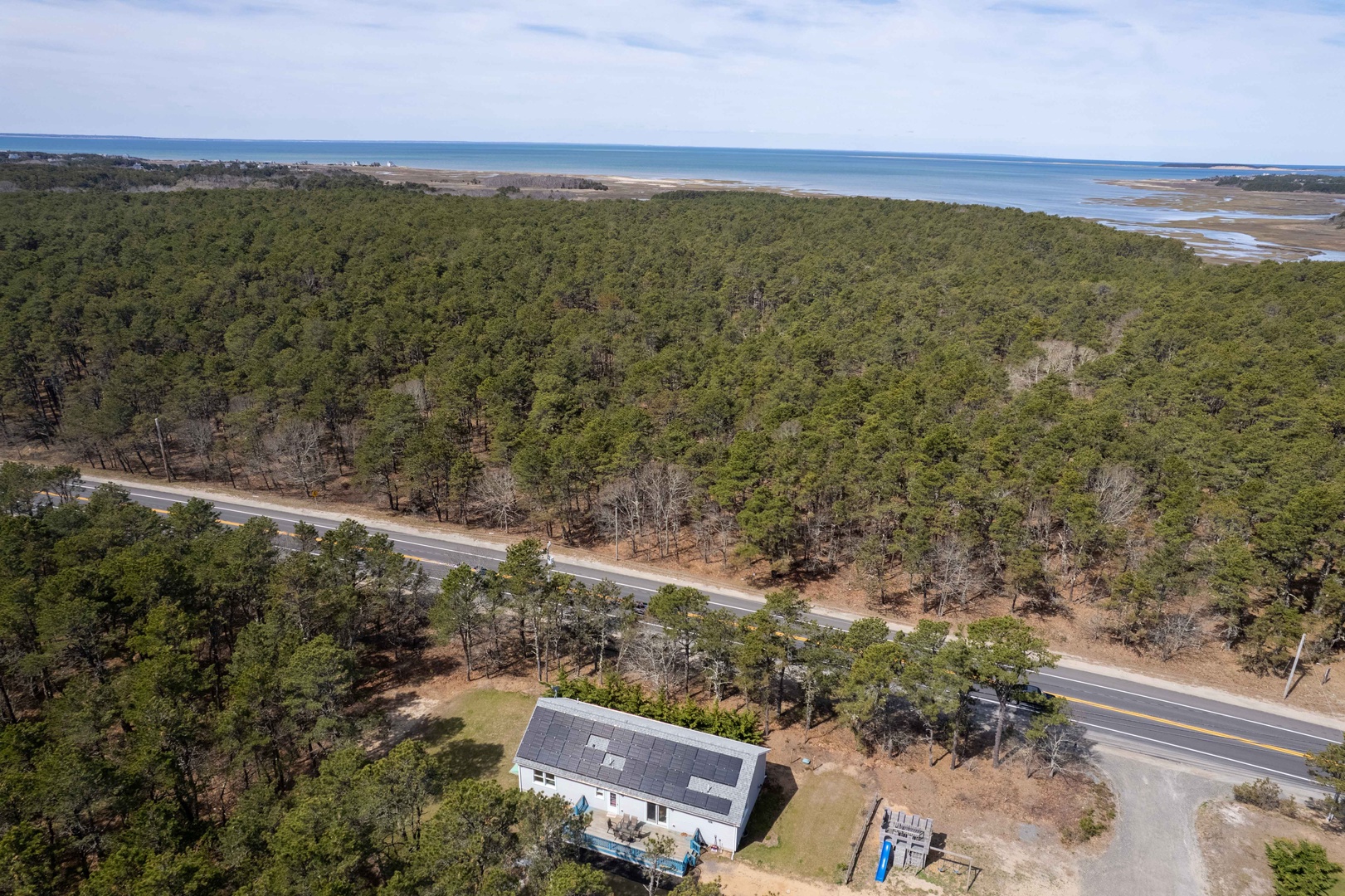 Aerial view showcasing the property's prime location nestled between dense coastal forest and pristine shoreline waters.